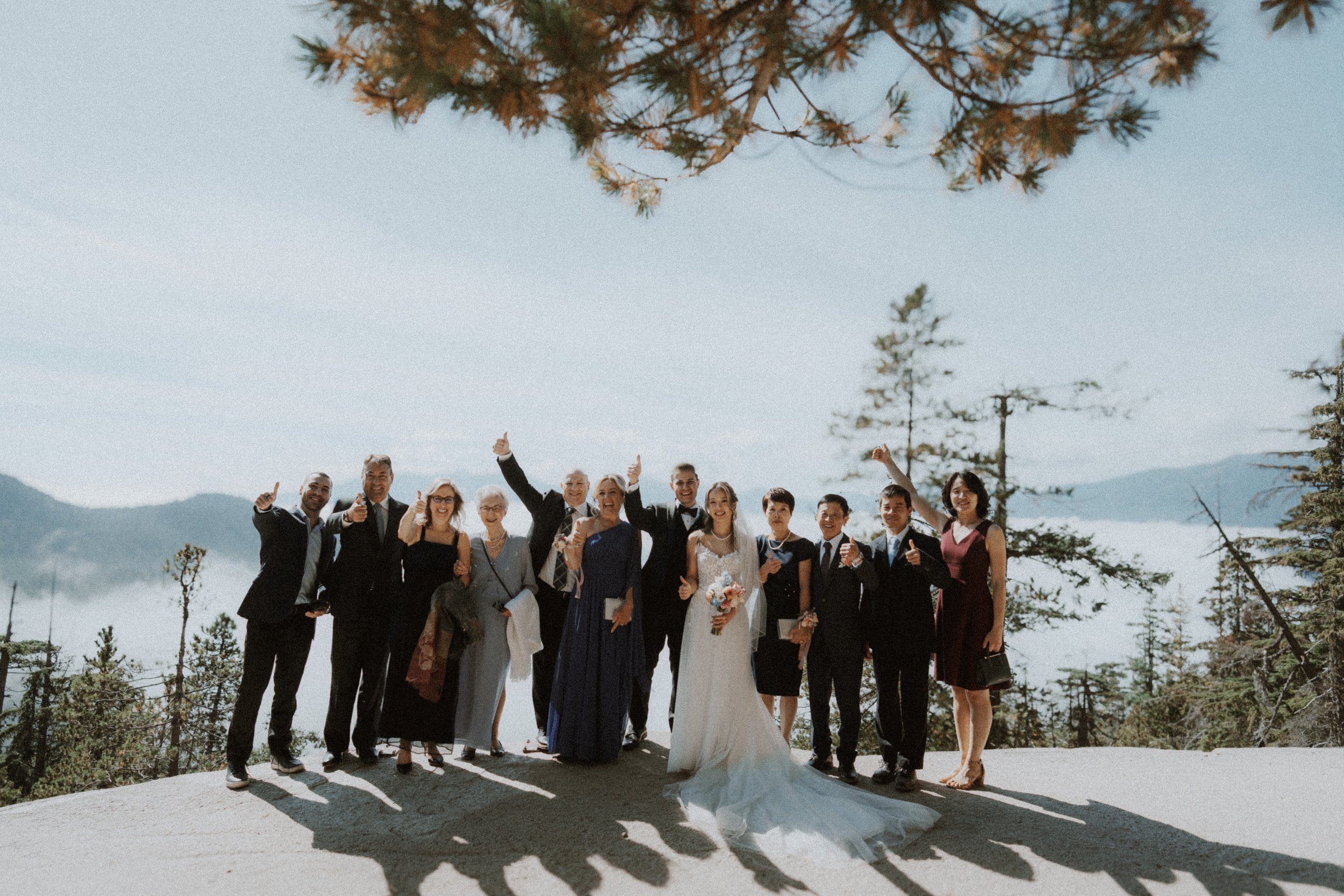 Wedding guests waving during a group portrait above the mountain valley.