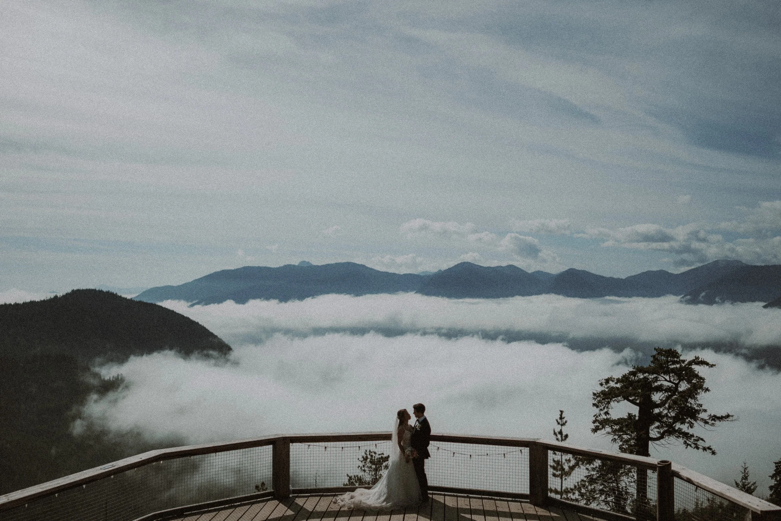 Wide mountain landscape with the newlyweds together on a viewing deck.