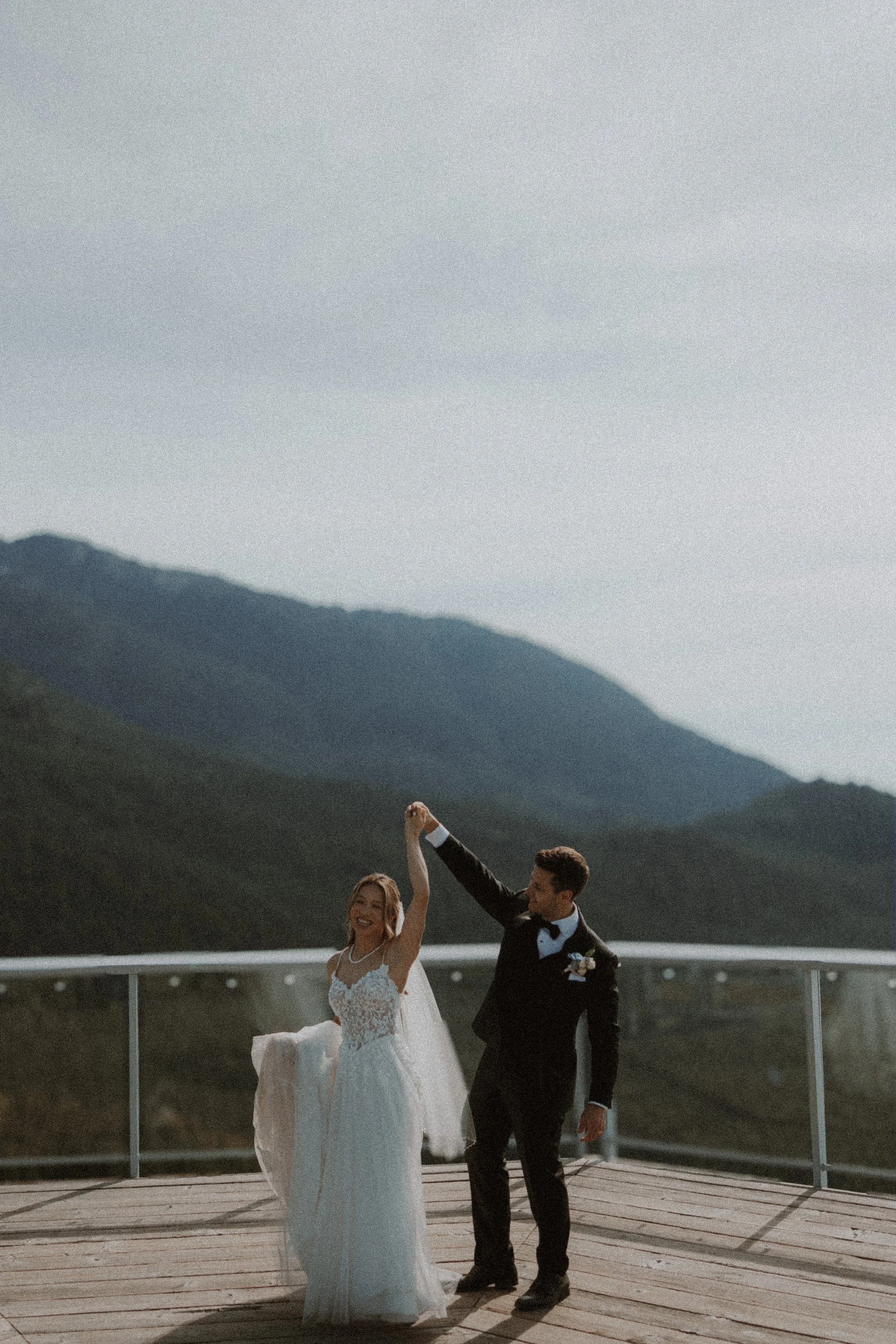 Wide portrait of the bride and groom dancing on the timber viewing platform.
