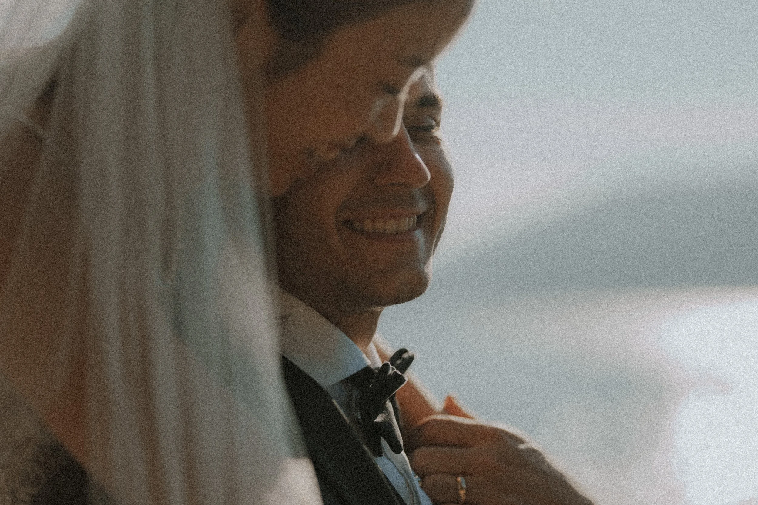 Close-up of the newlyweds laughing beneath the bride's veil.