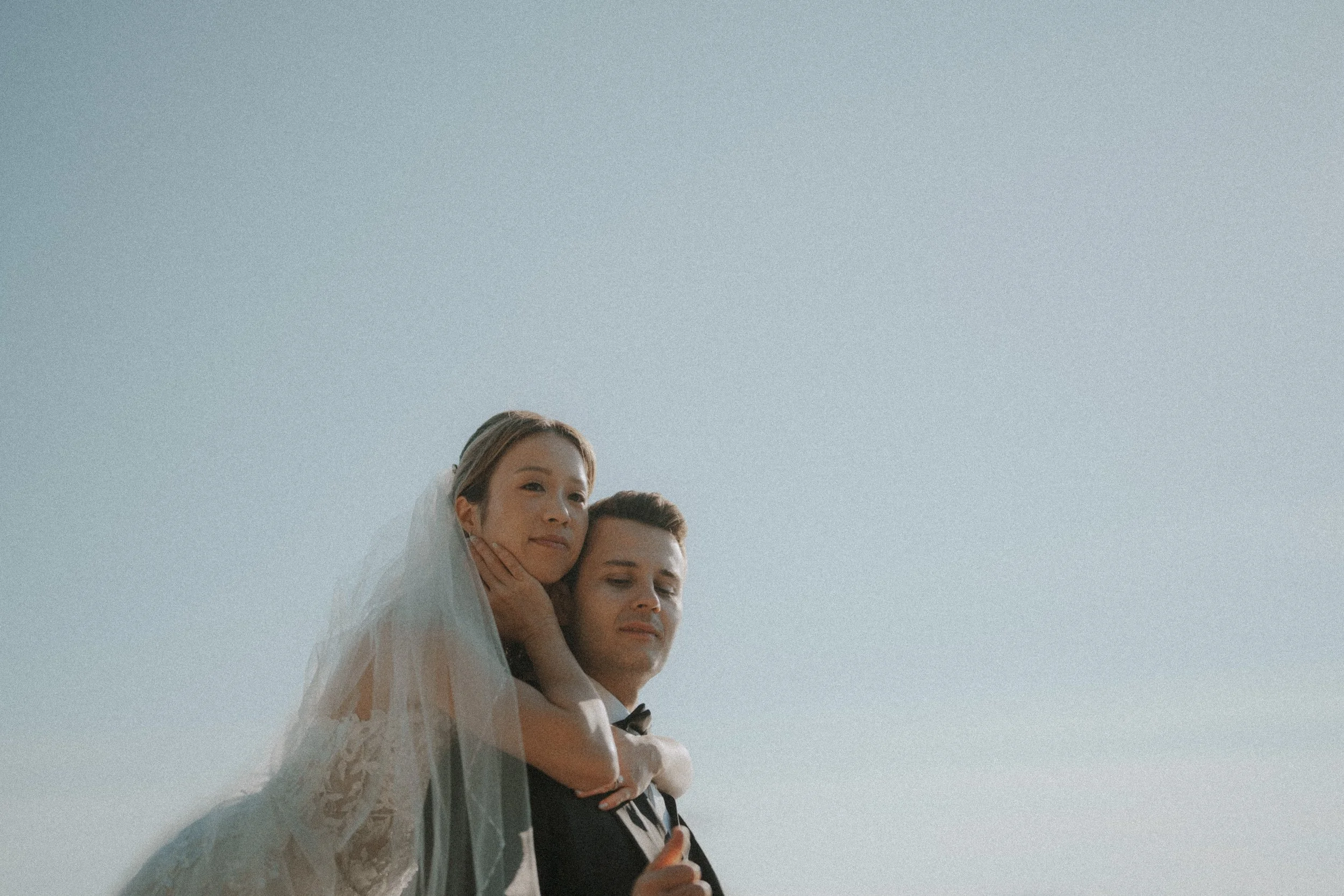 Couple looking into the distance while embracing beside the water.