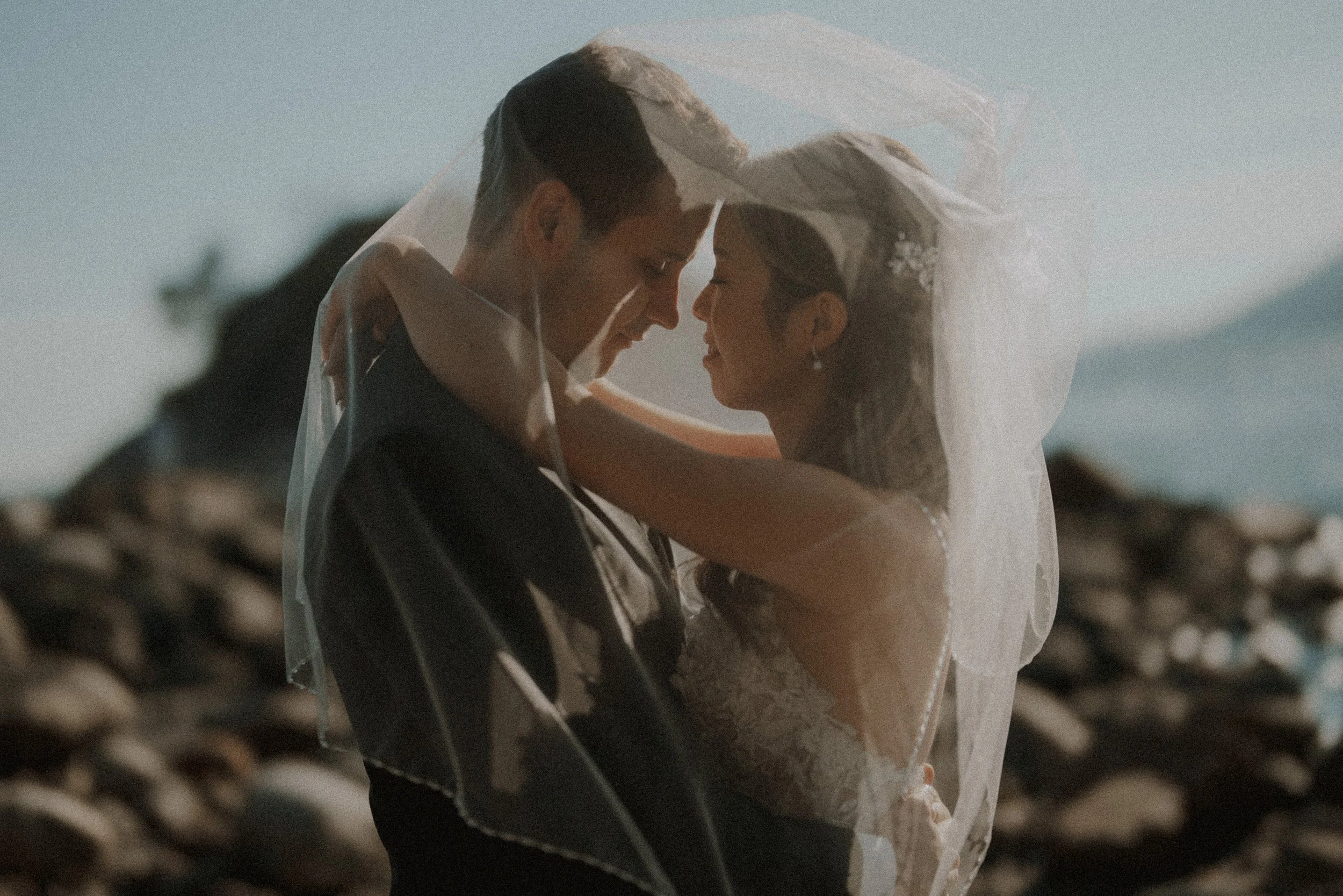 Newlyweds touching foreheads beneath the bride's veil.