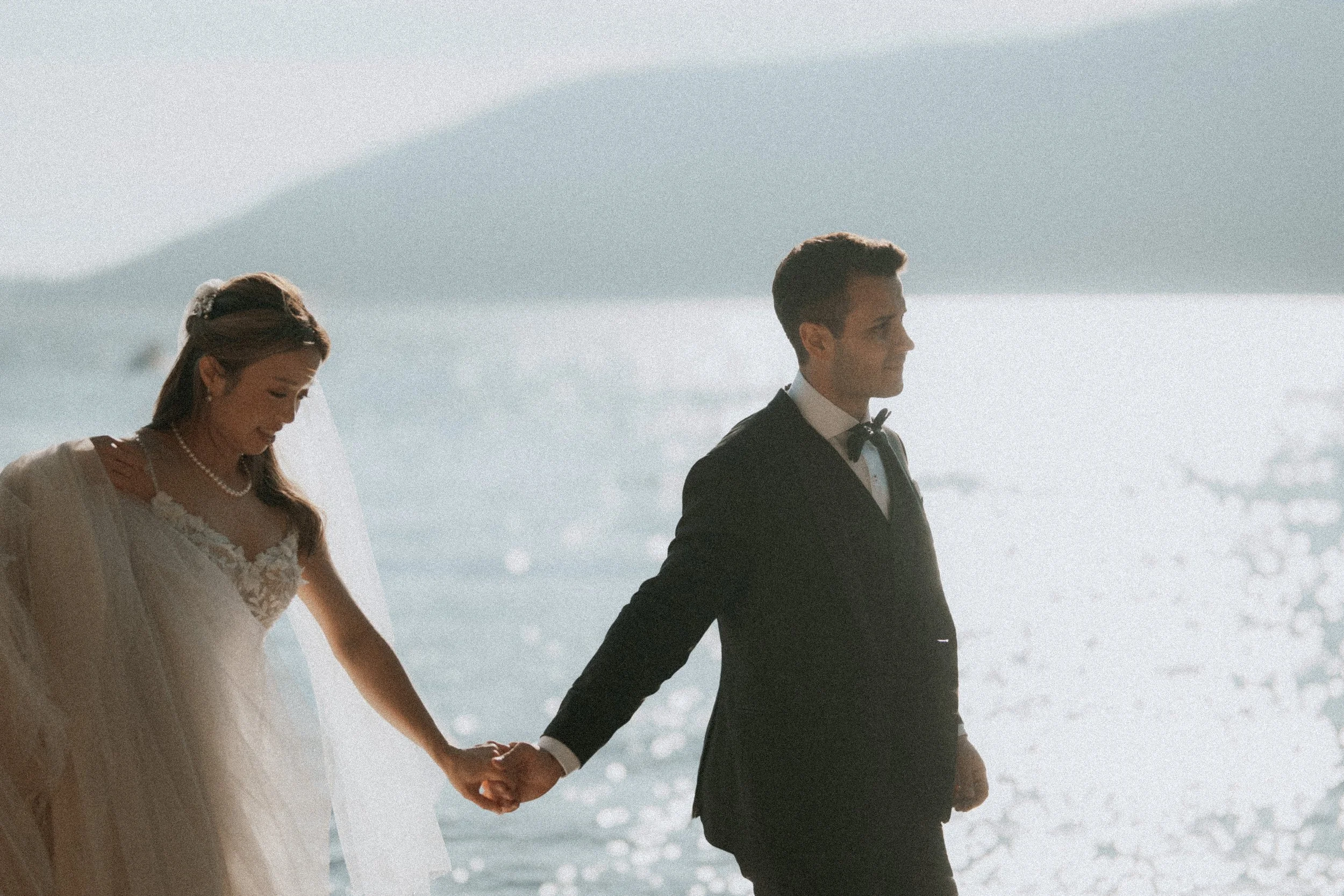 Couple holding hands in bright coastal sunlight.
