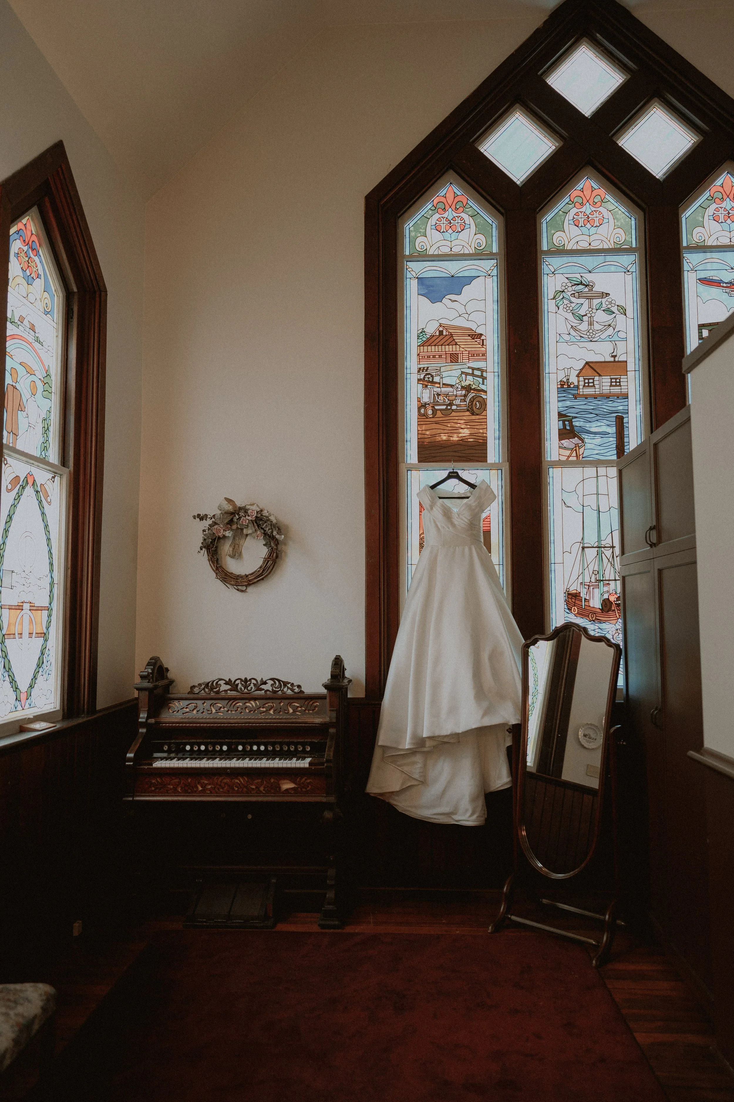 Wedding dress hanging beside stained-glass windows in Minoru Chapel.