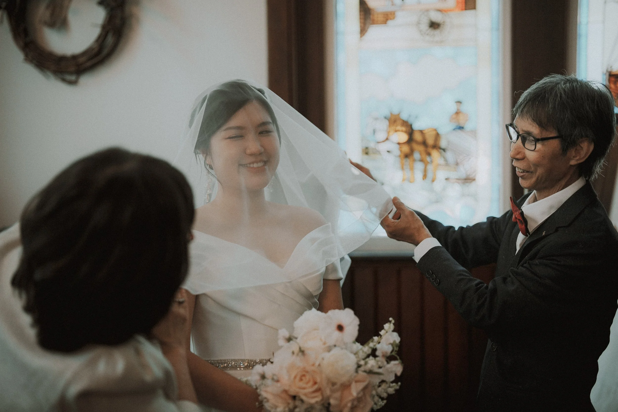 Guest arranging the bride's veil around her shoulders before the ceremony.