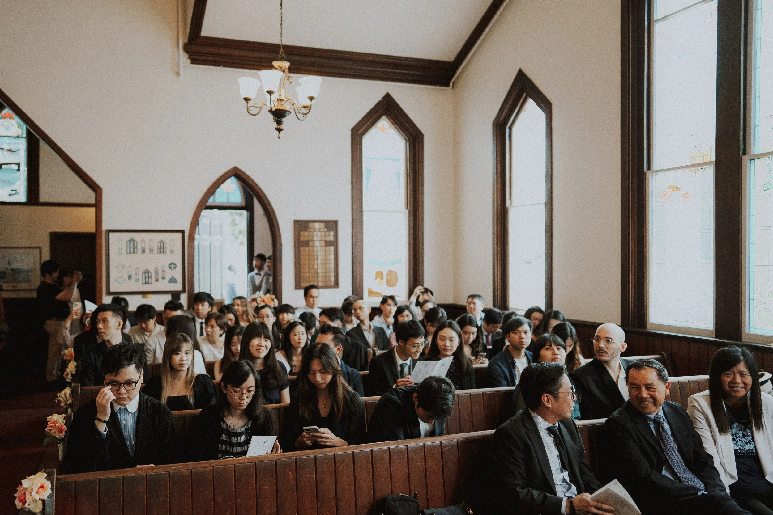 Wedding guests smiling from the wooden pews inside Minoru Chapel.