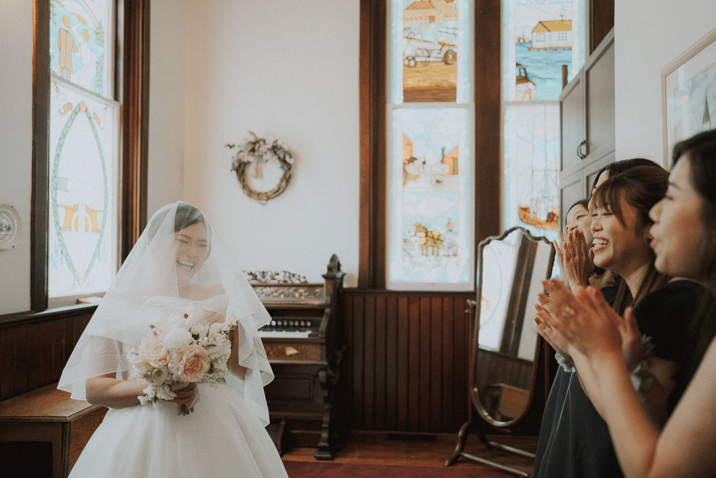 Bride holding her bouquet as guests applaud beside the chapel doorway.
