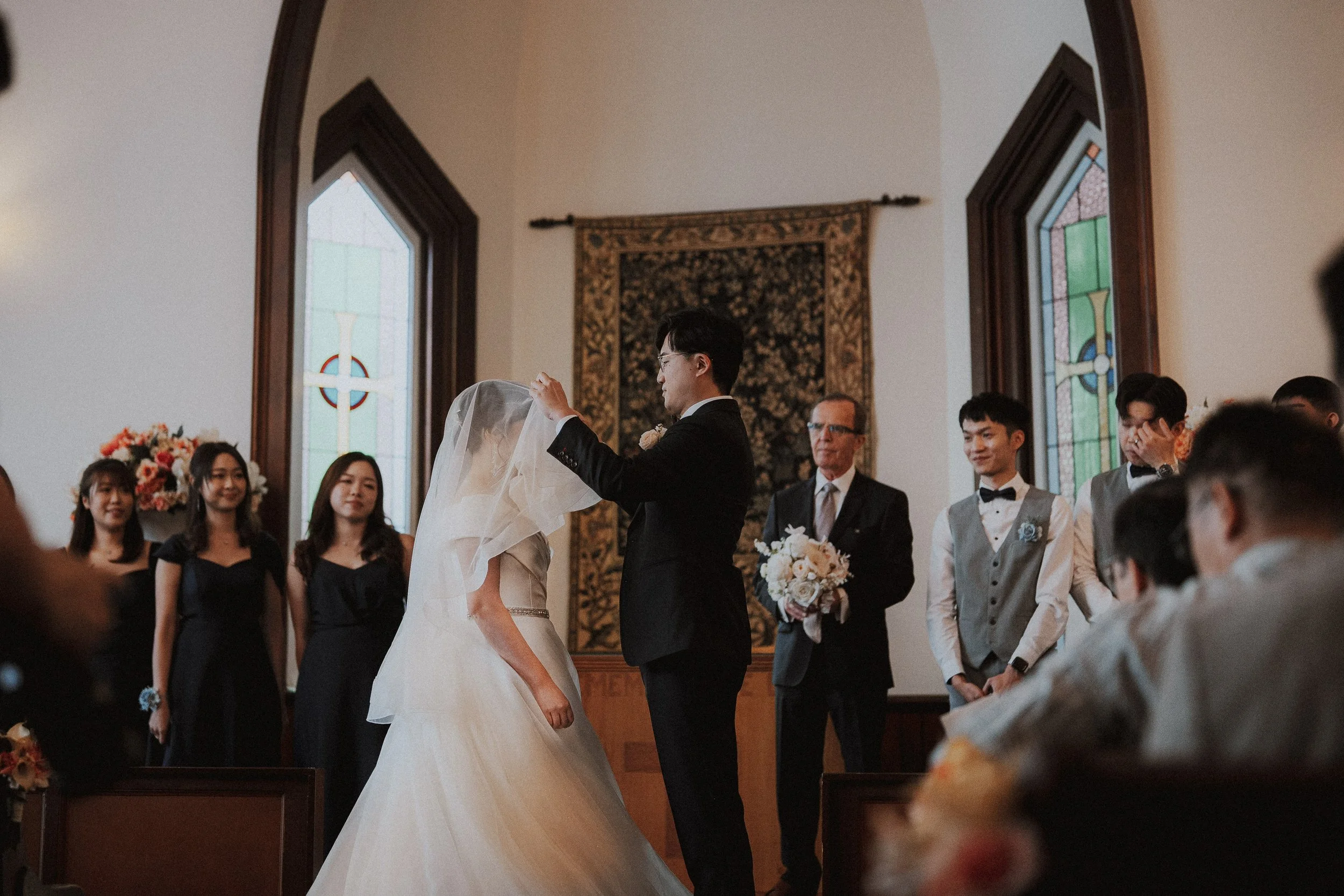 Groom lifting the bride's veil before their vows.