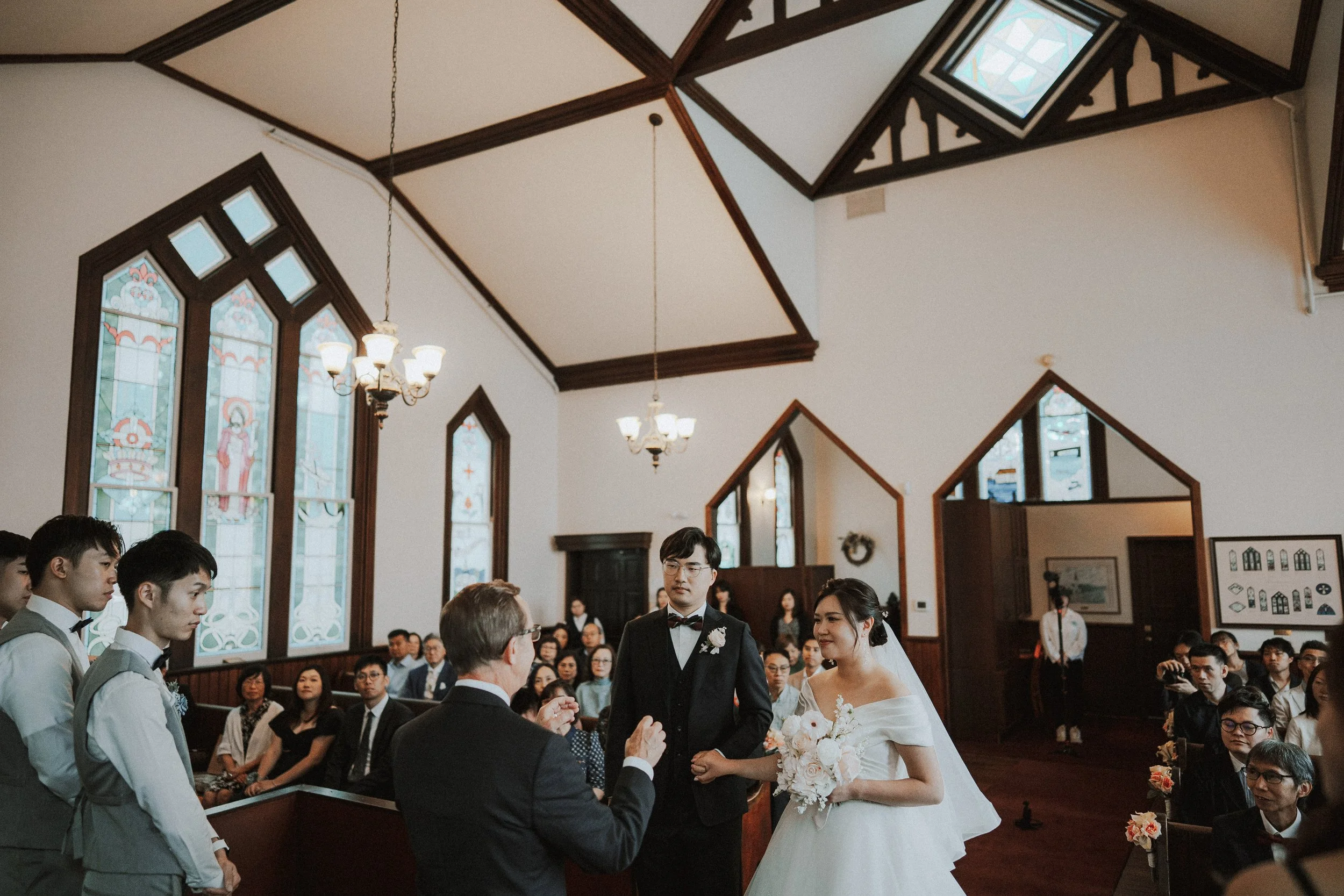 Bride and groom standing before the officiant inside Minoru Chapel.