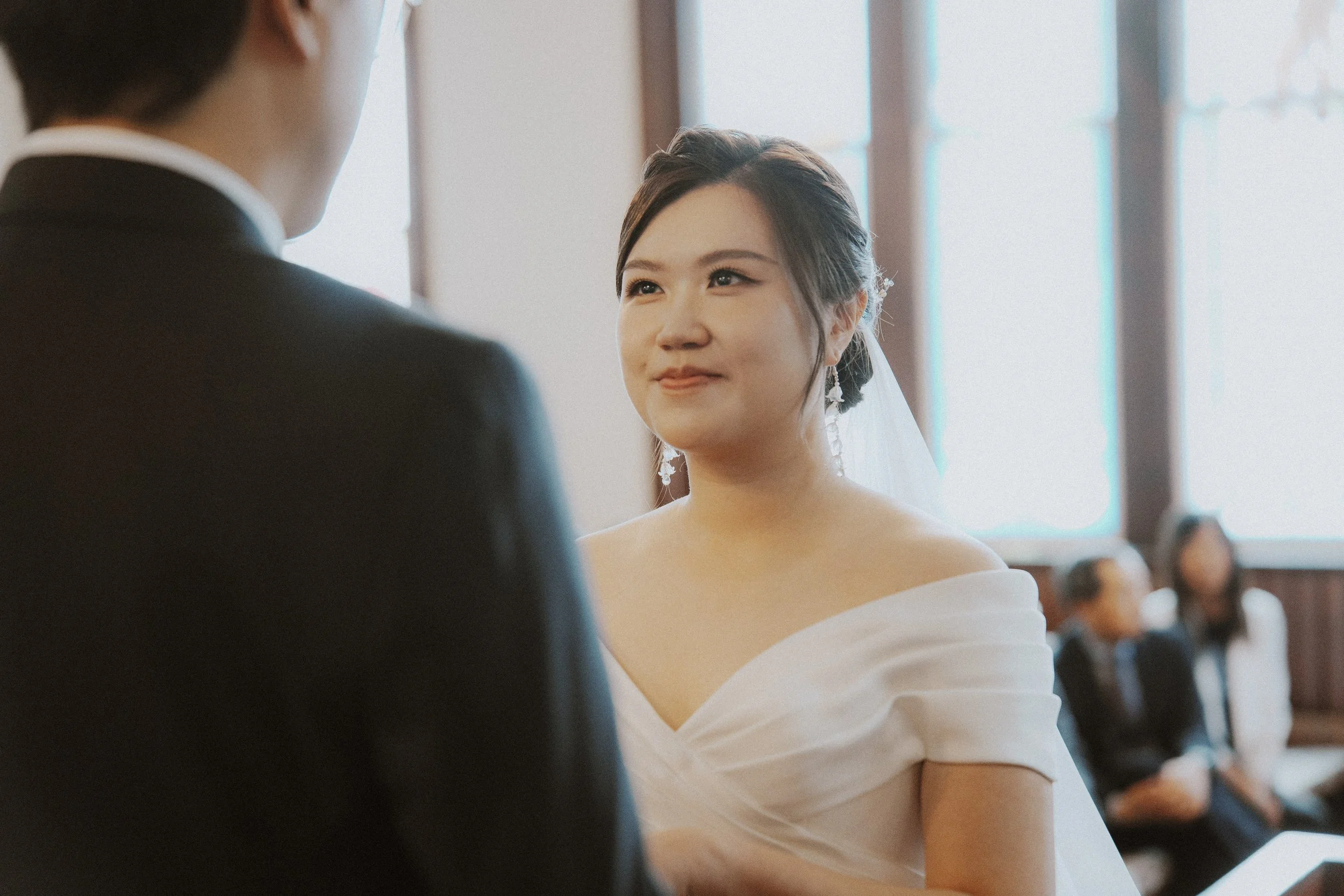 Bride smiling at the groom during their wedding vows.