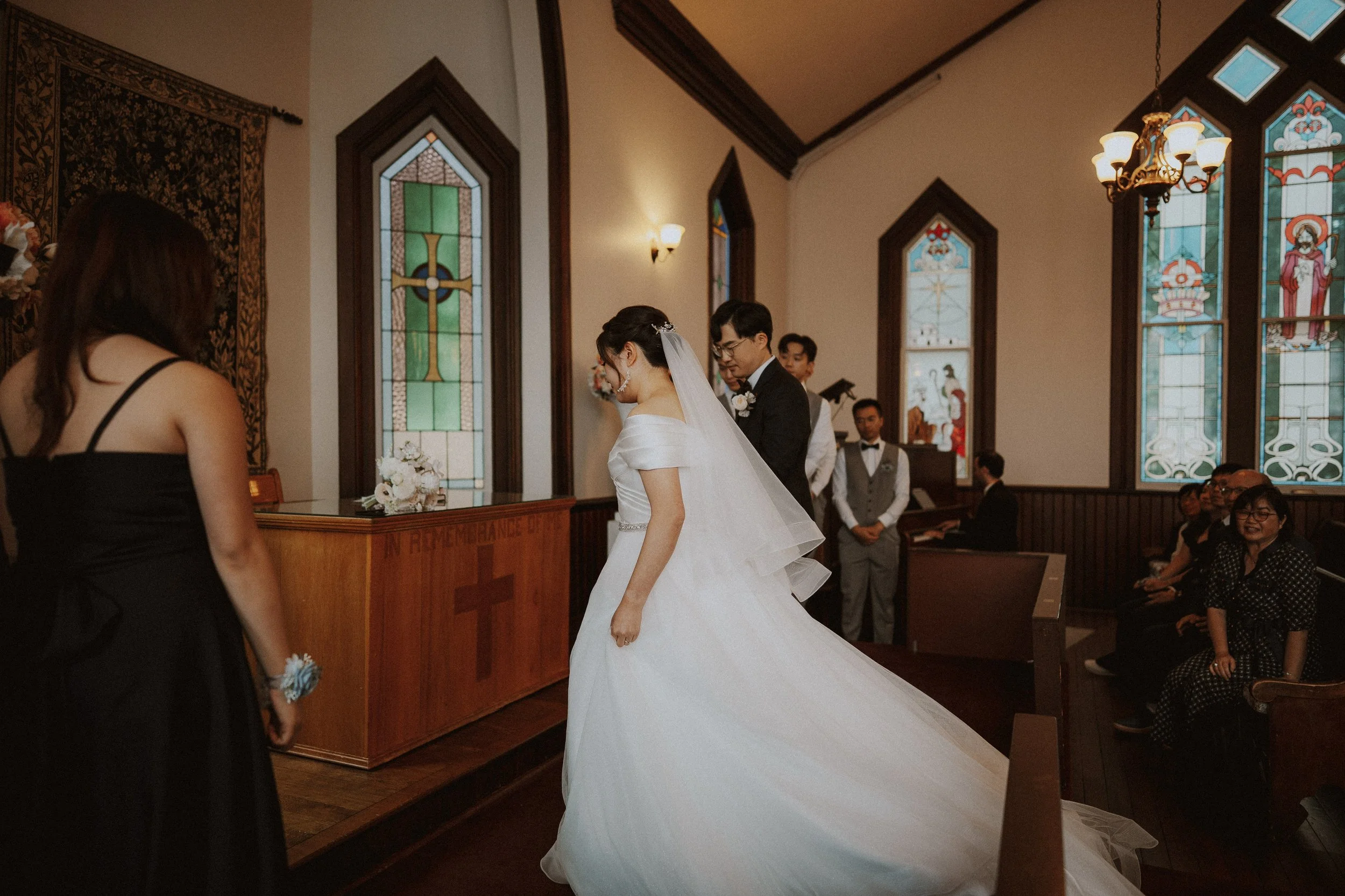 Bride's gown sweeping across the chapel floor as she turns beside the groom.