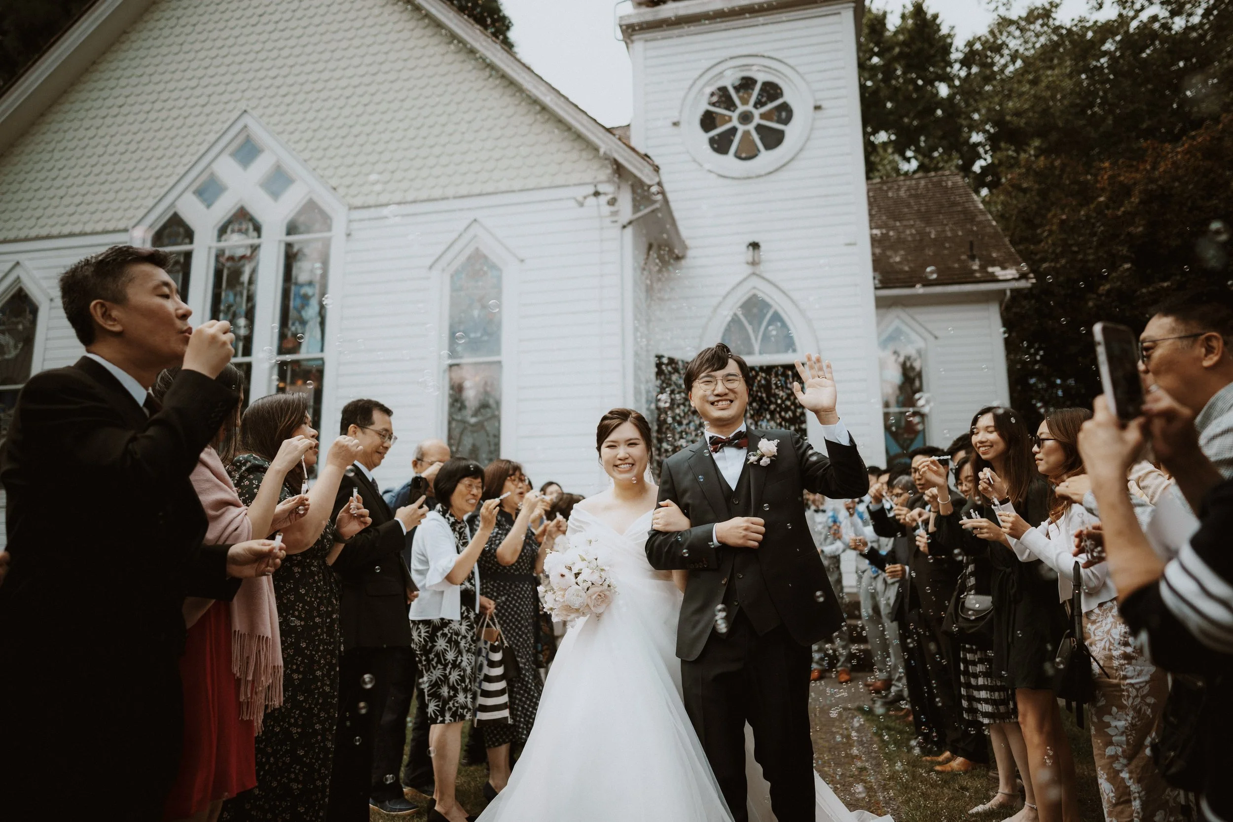 Newlyweds greeted by guests blowing bubbles outside Minoru Chapel.