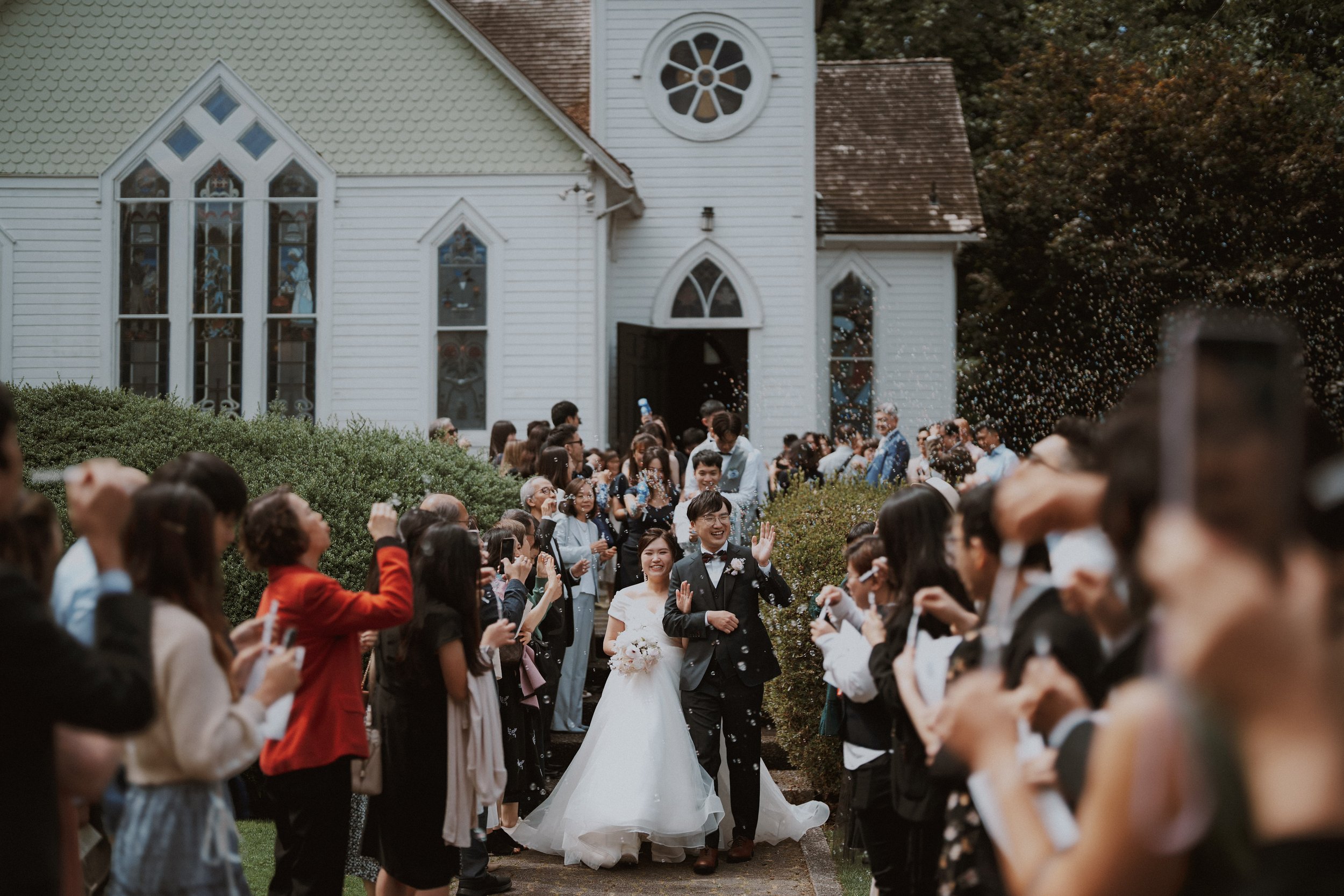 Bride and groom walking through a crowd of celebrating guests outside Minoru Chapel.