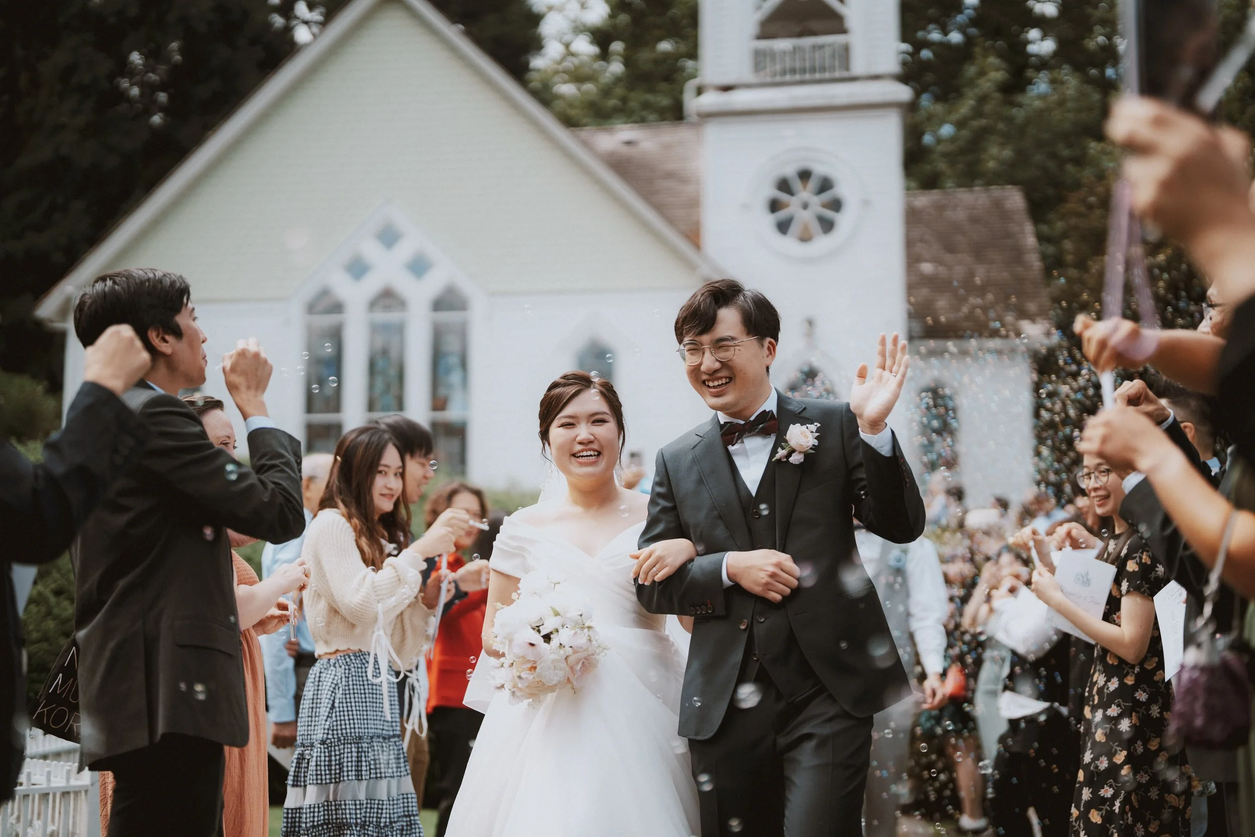 Bride and groom waving to guests during their bubble-filled chapel exit.