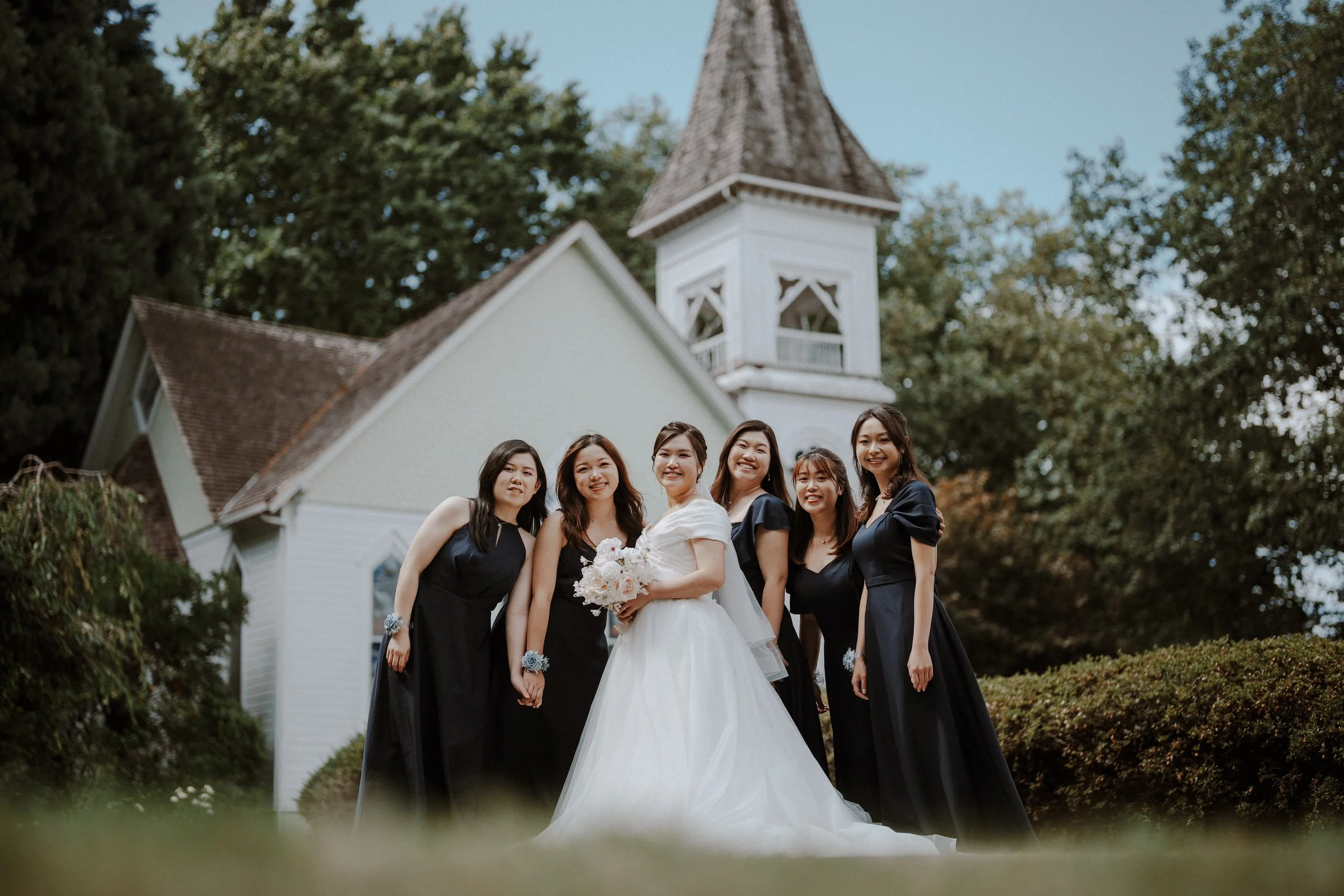 Bride and bridesmaids posing together beneath the chapel tower.
