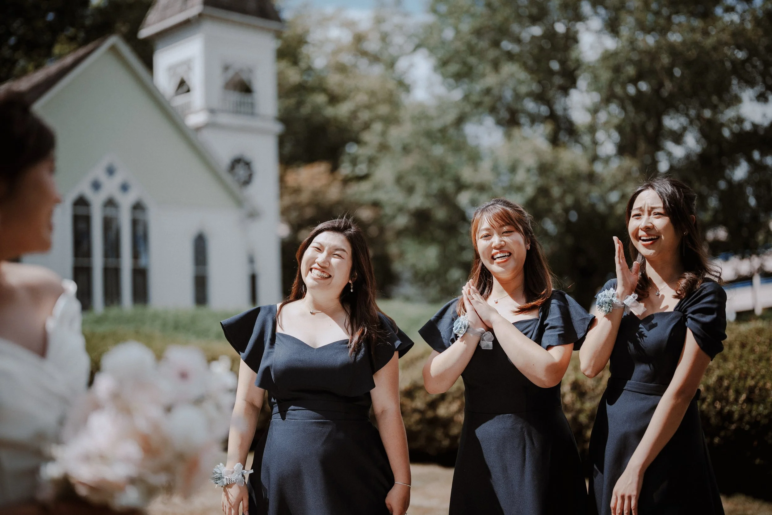 Bridesmaids smiling and applauding in the chapel gardens.