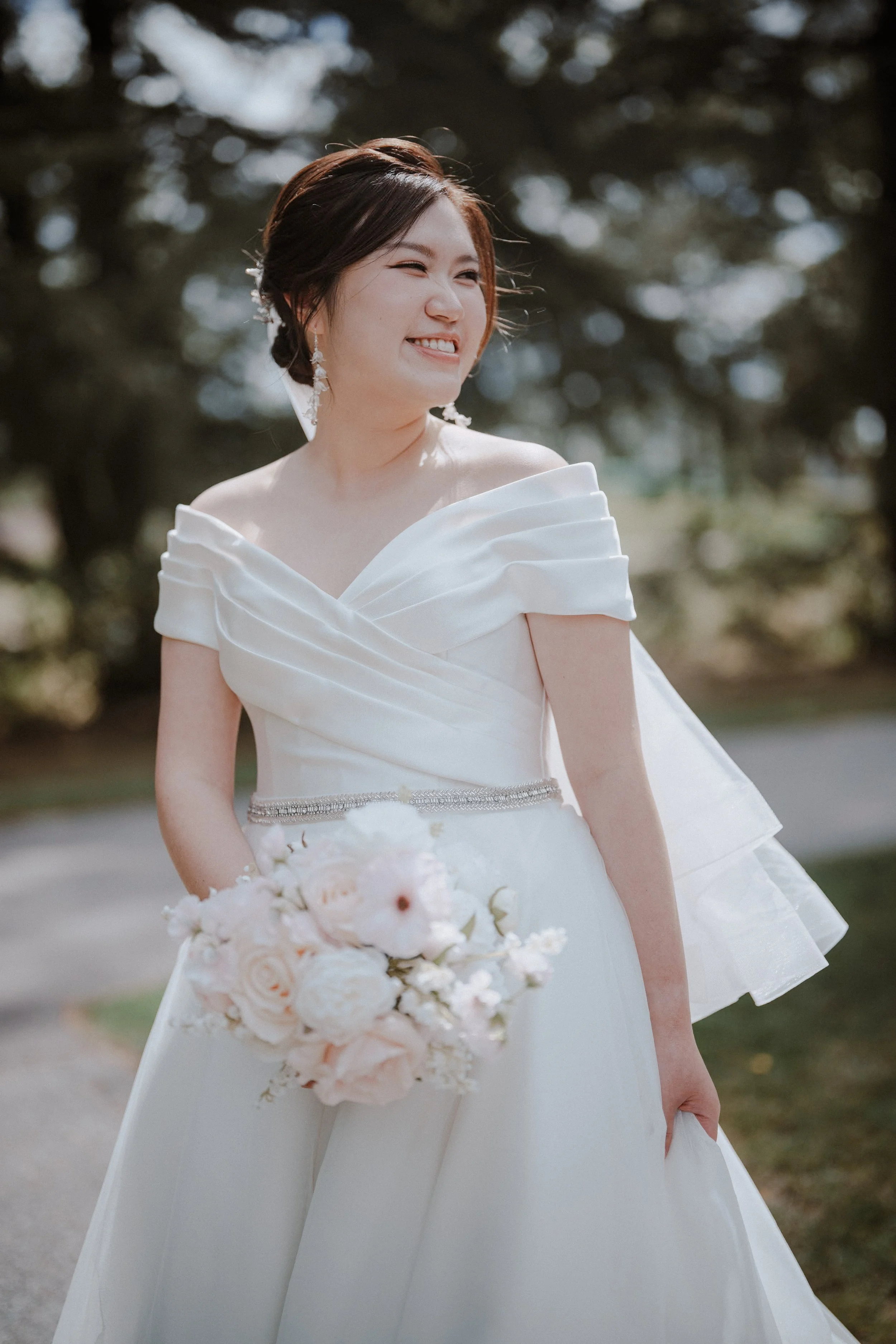 Bride looking to the side with her bouquet in the chapel gardens.