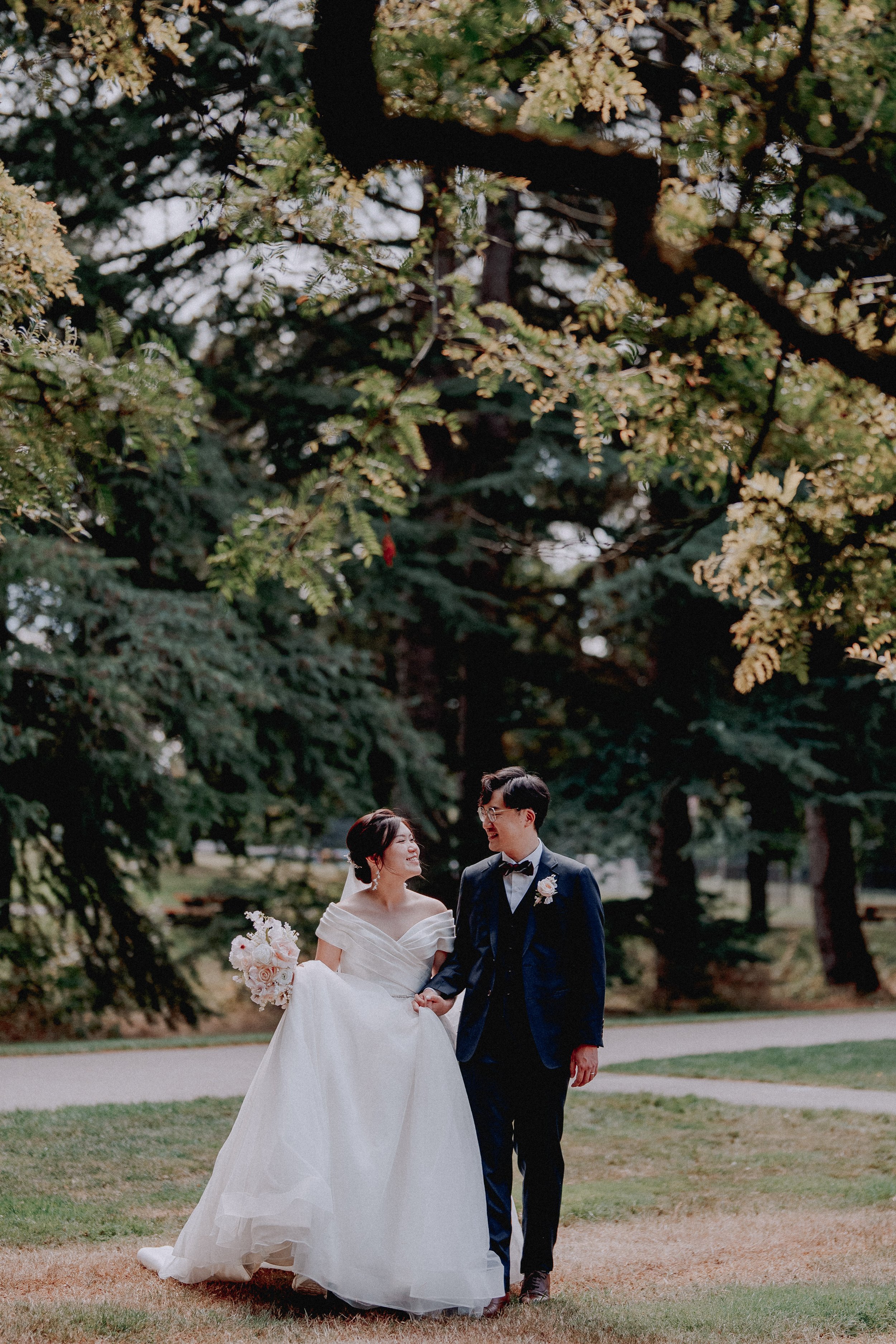 Bride and groom walking together through a leafy garden.