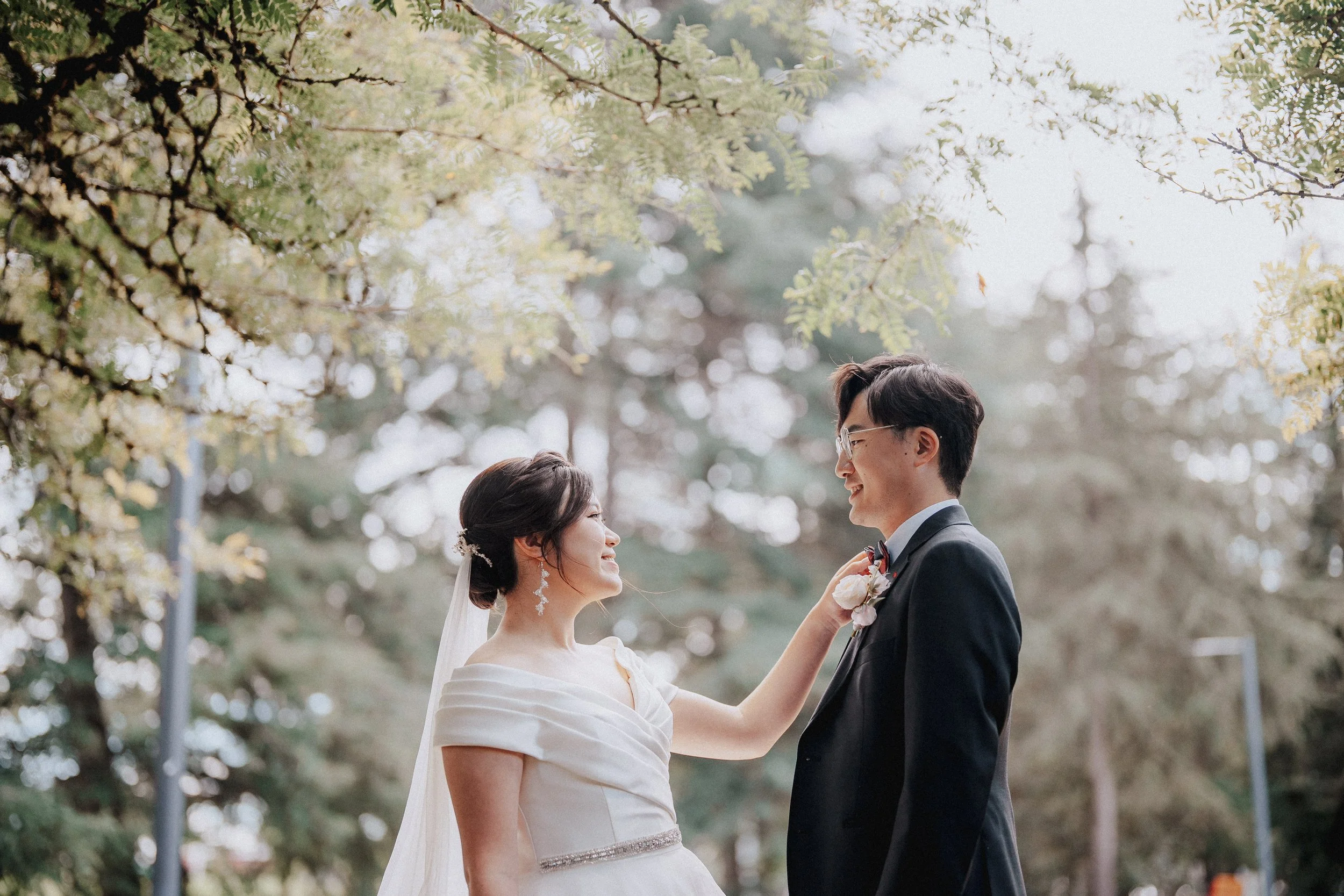 Bride adjusting the groom's lapel as they smile at each other.