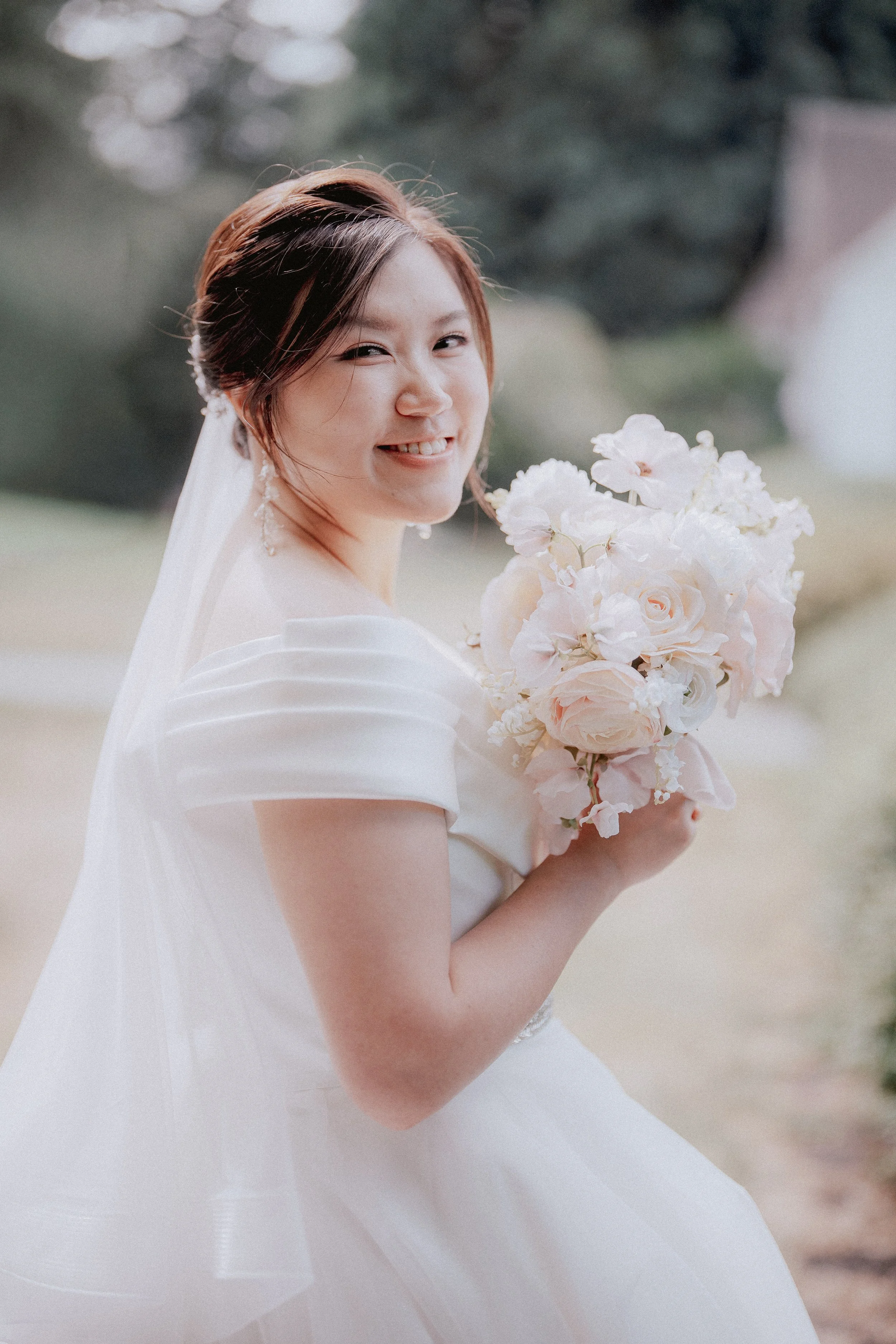 Bride smiling over her shoulder while holding her bouquet.
