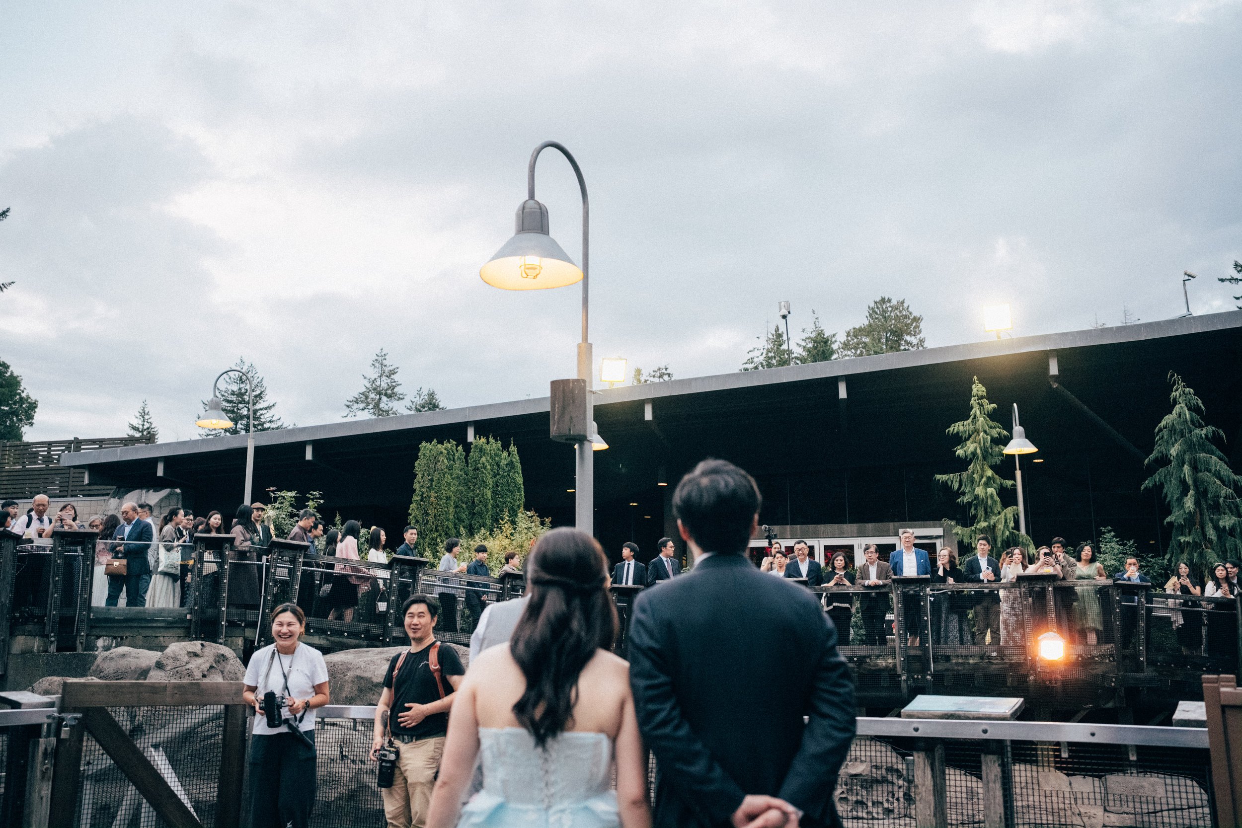 Couple approaching wedding guests gathered on the Vancouver Aquarium terrace.
