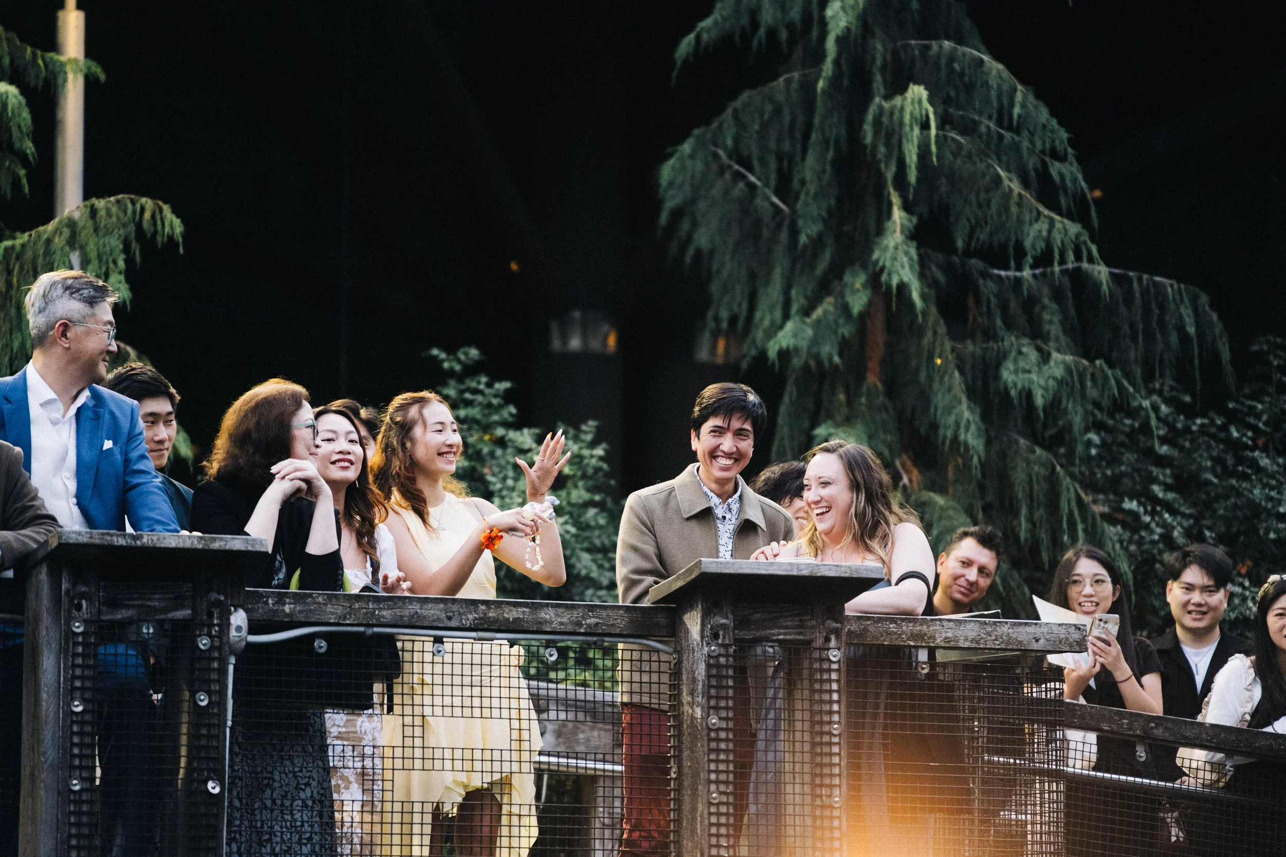 Wedding guests laughing and gesturing from the reception terrace.