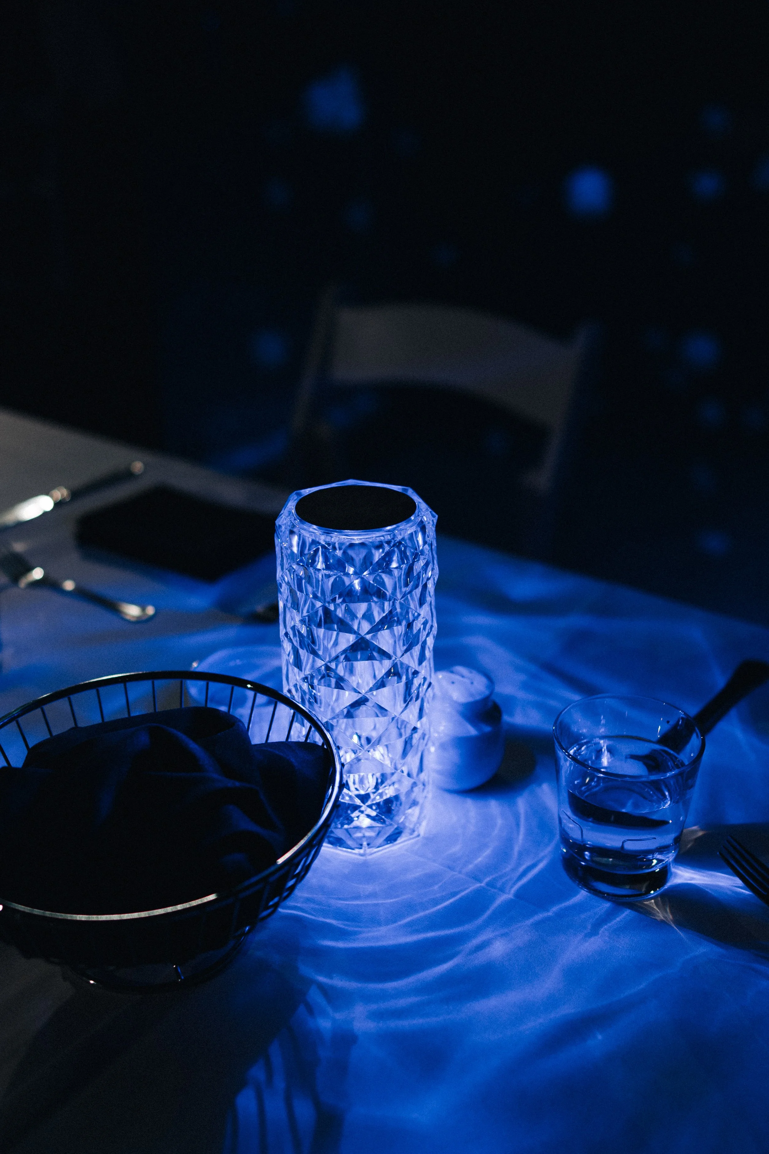 Blue-lit cut-glass candle holder and place setting at the wedding reception.