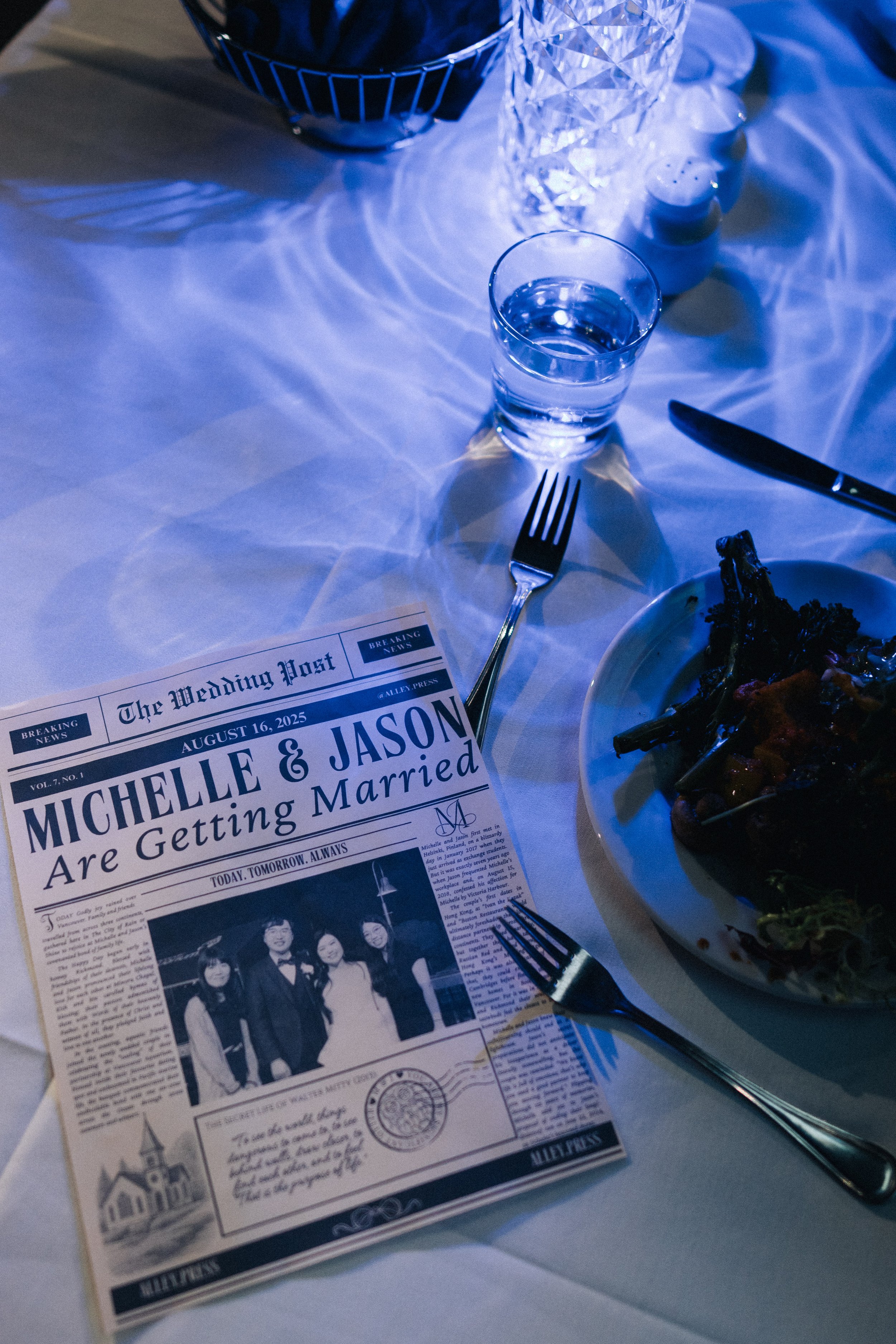 Wedding newspaper and tableware illuminated by blue aquarium light.