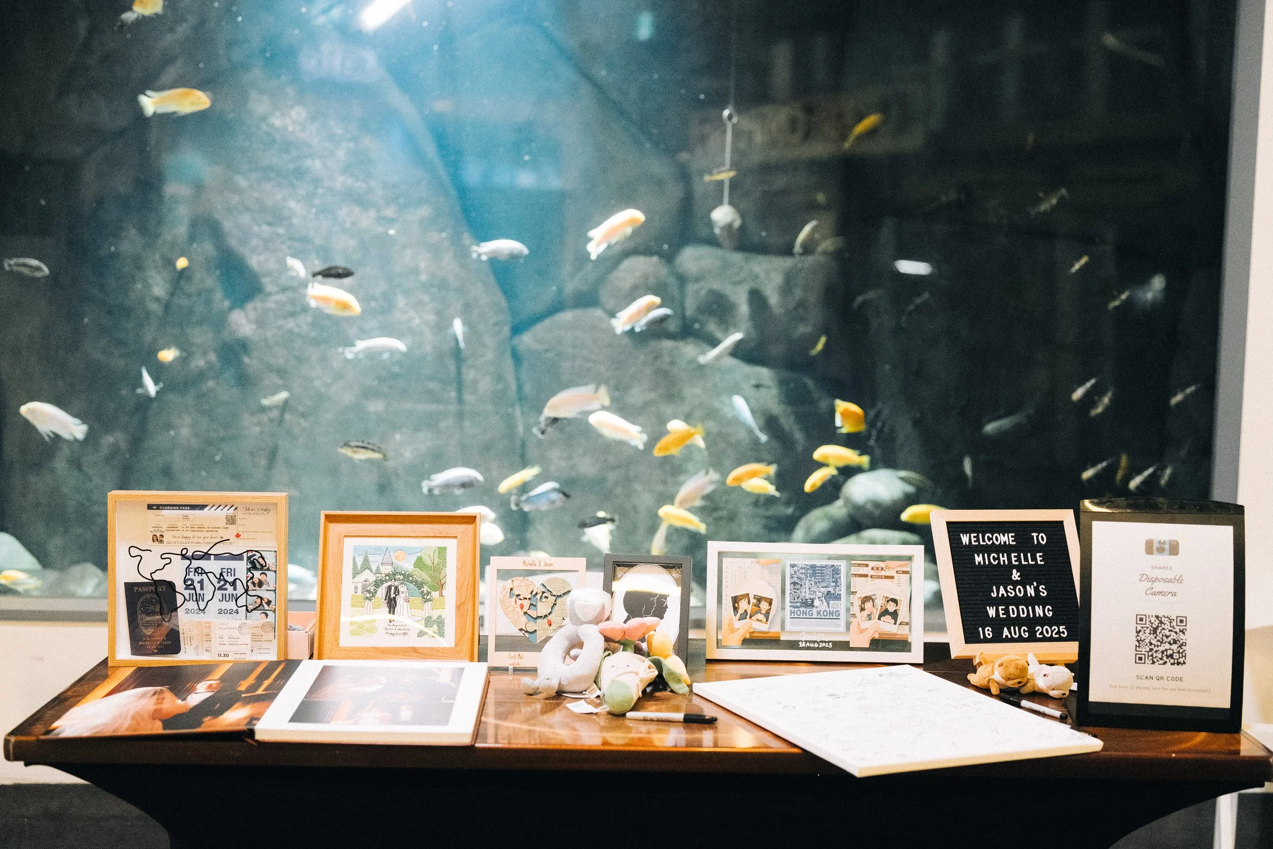 Welcome table with framed photographs in front of a Vancouver Aquarium fish display.