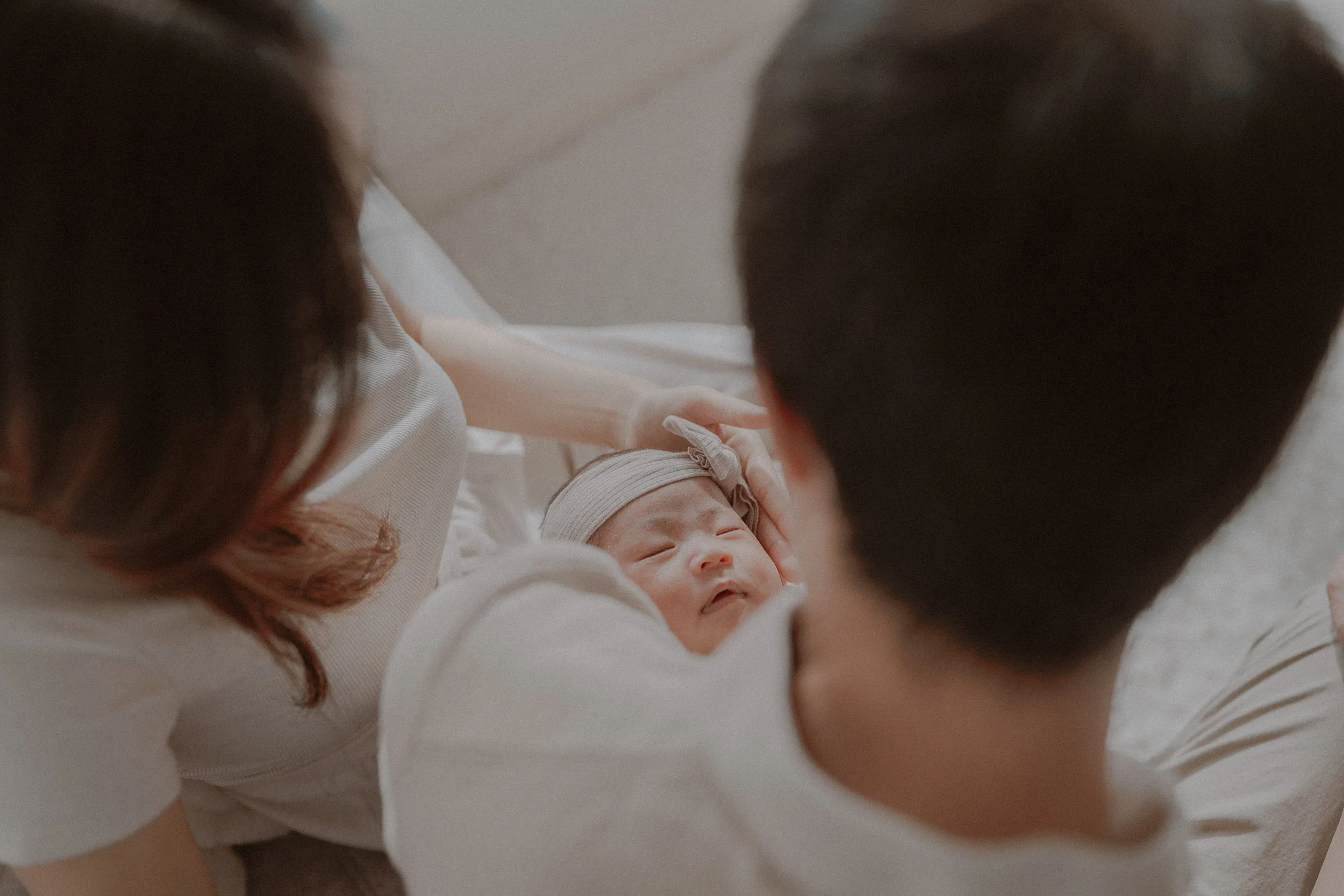 Parents looking down at their newborn during a quiet family moment.