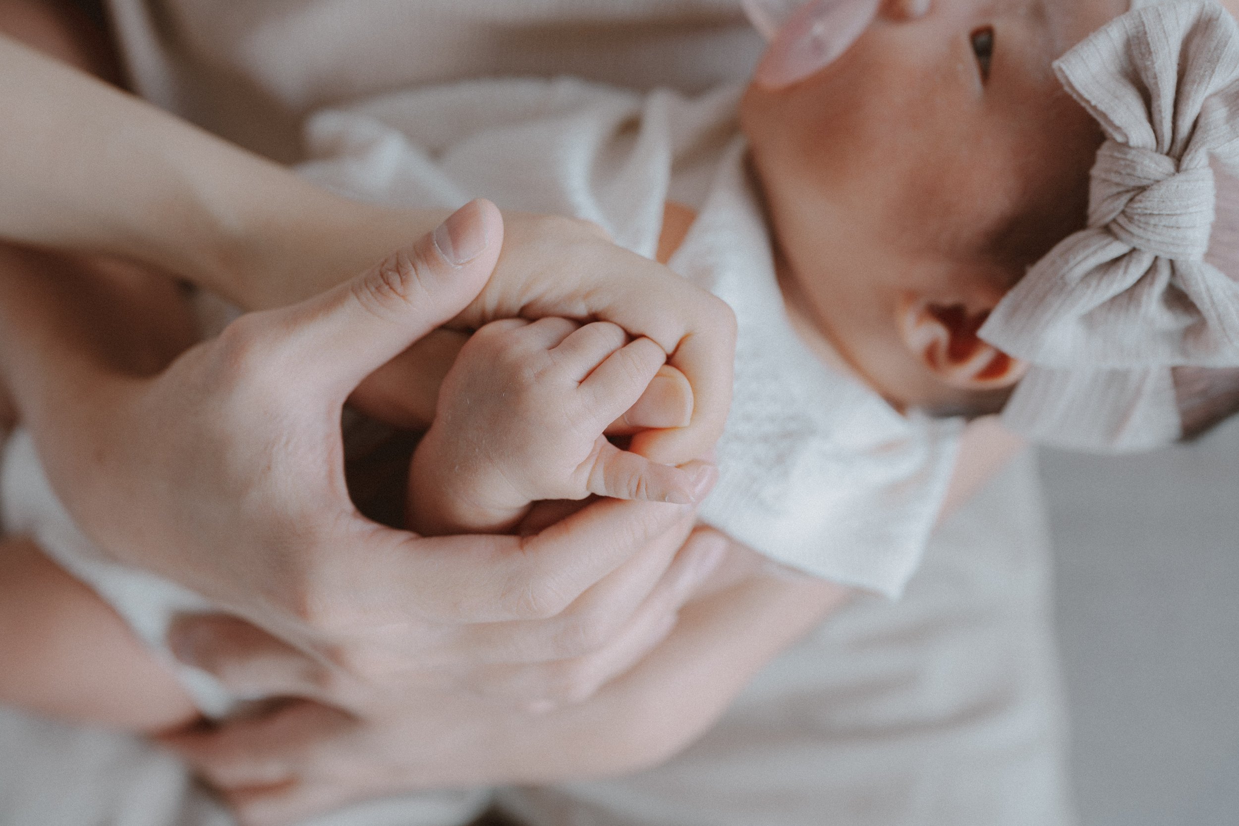 Newborn's tiny feet supported in a parent's cupped hands.