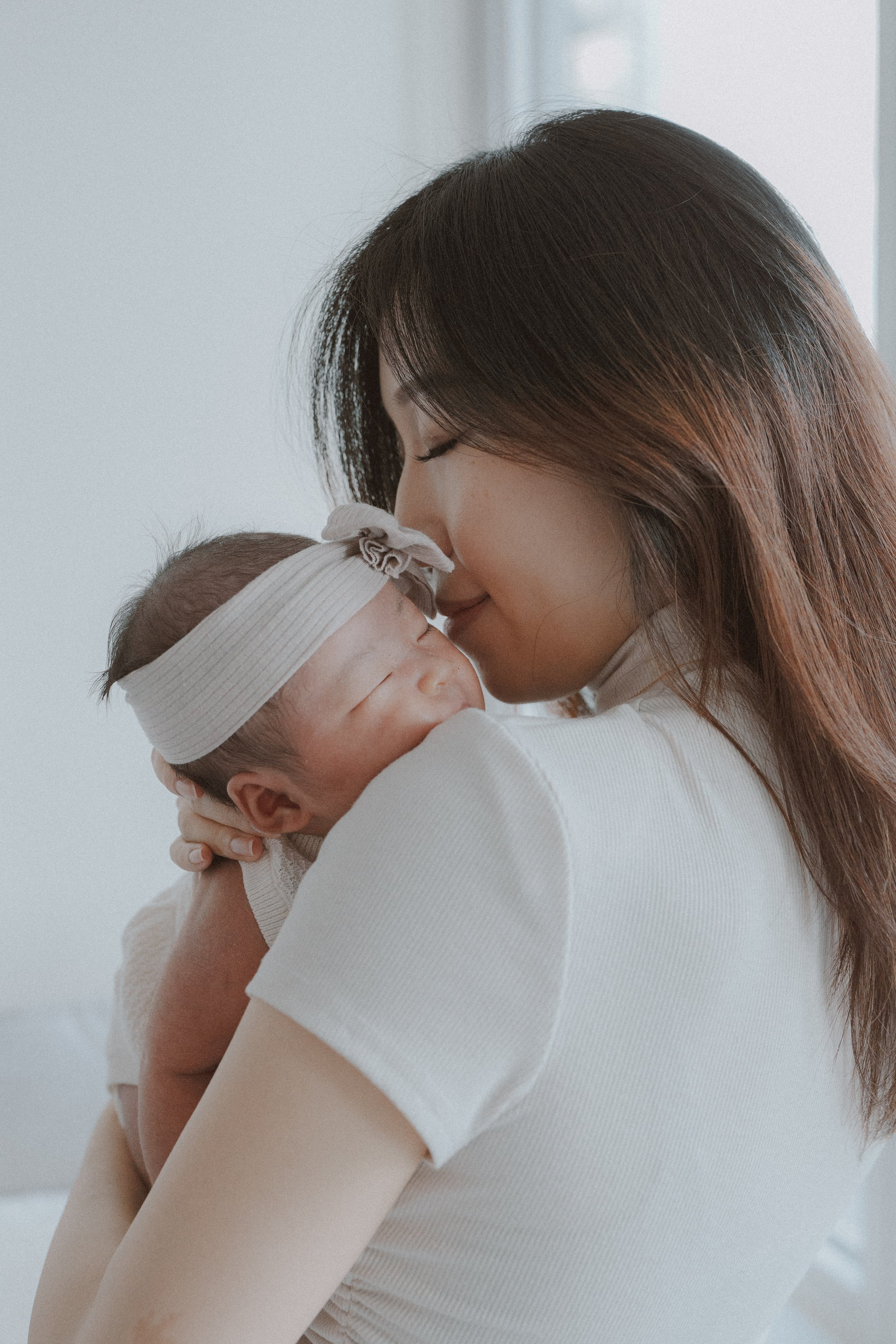 Parent kissing the newborn's forehead while holding the baby against their shoulder.