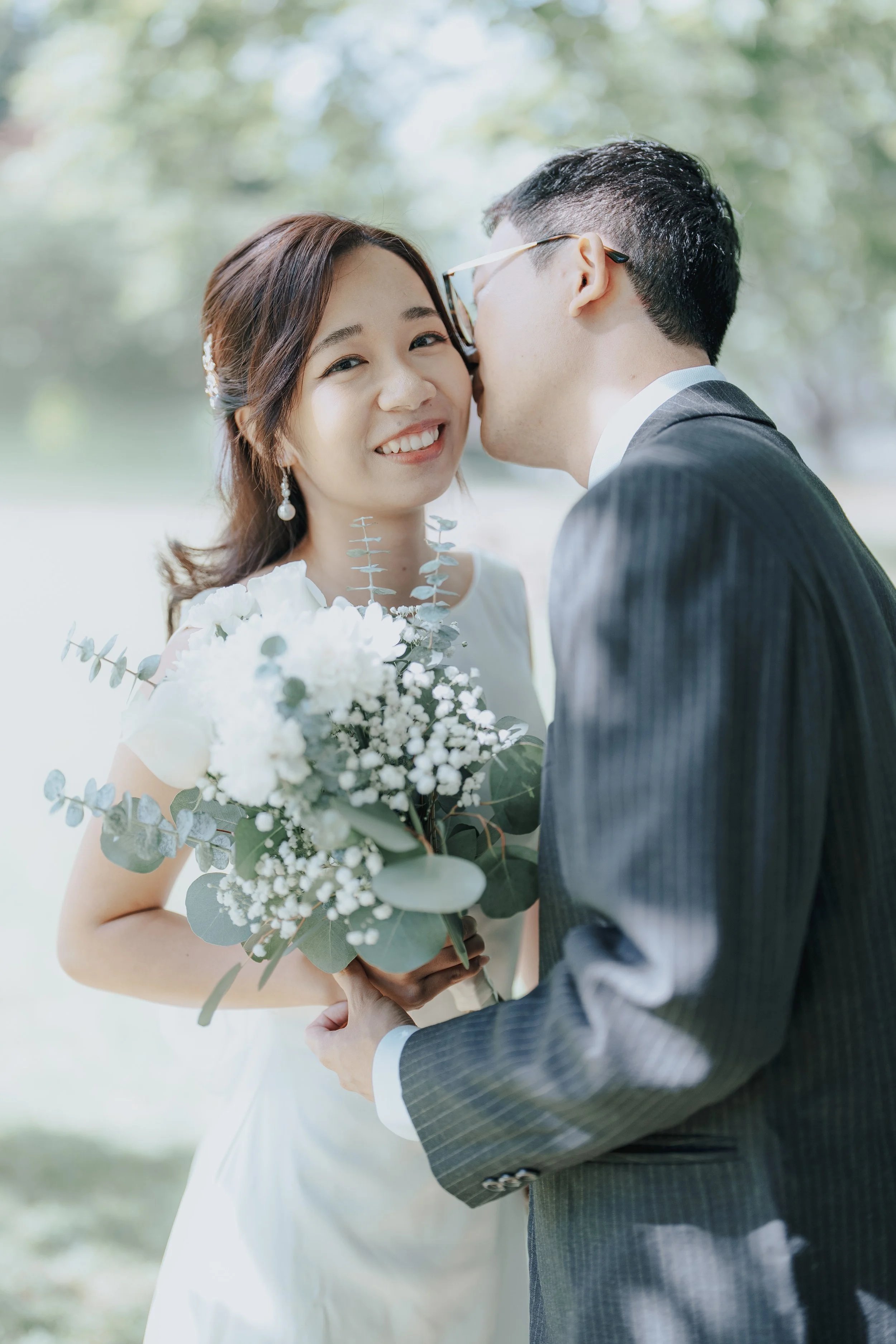 Chloe and Marco smiling together with a bouquet at Stanley Park, Vancouver