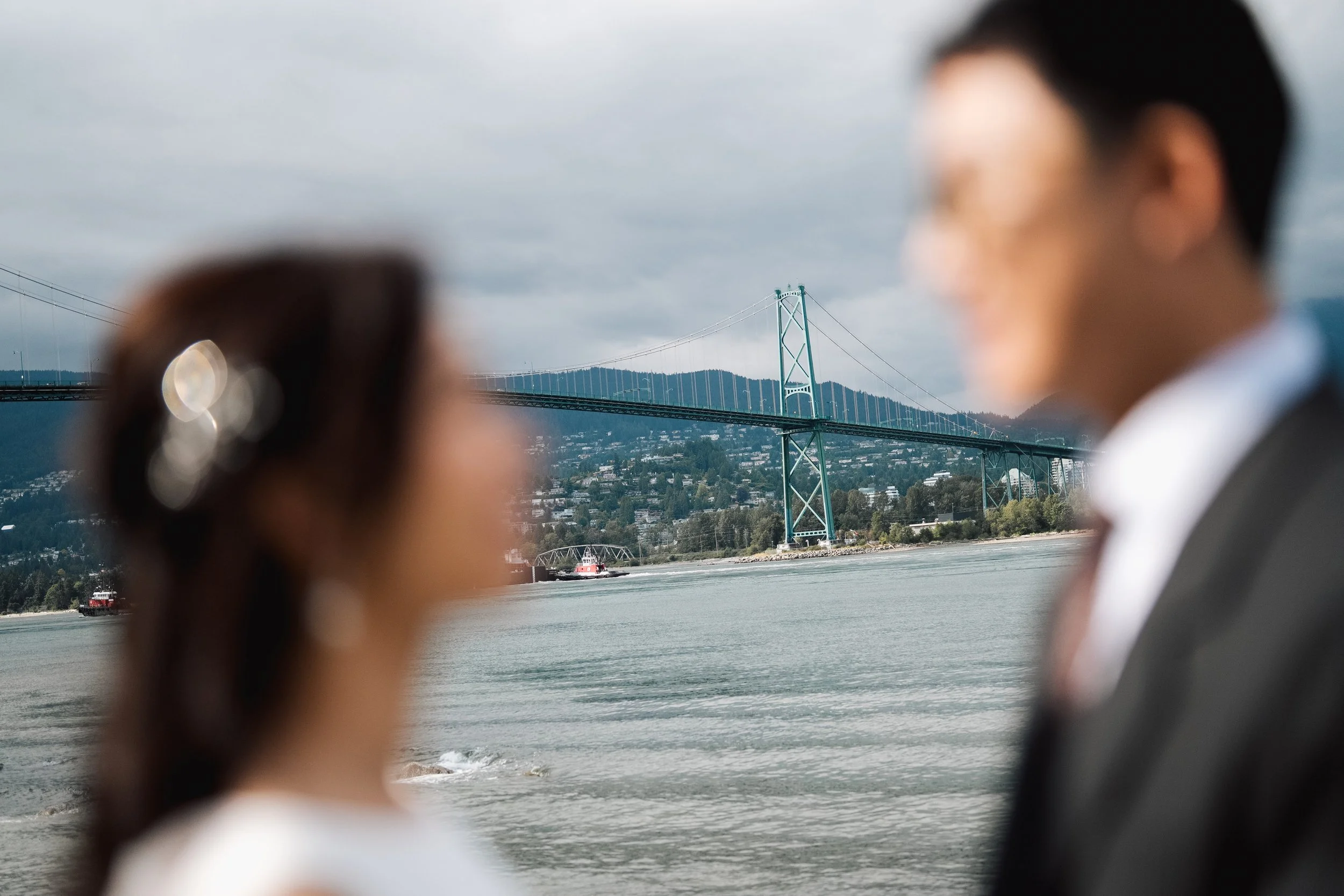 Chloe and Marco by Stanley Park waterfront with Lions Gate Bridge beyond
