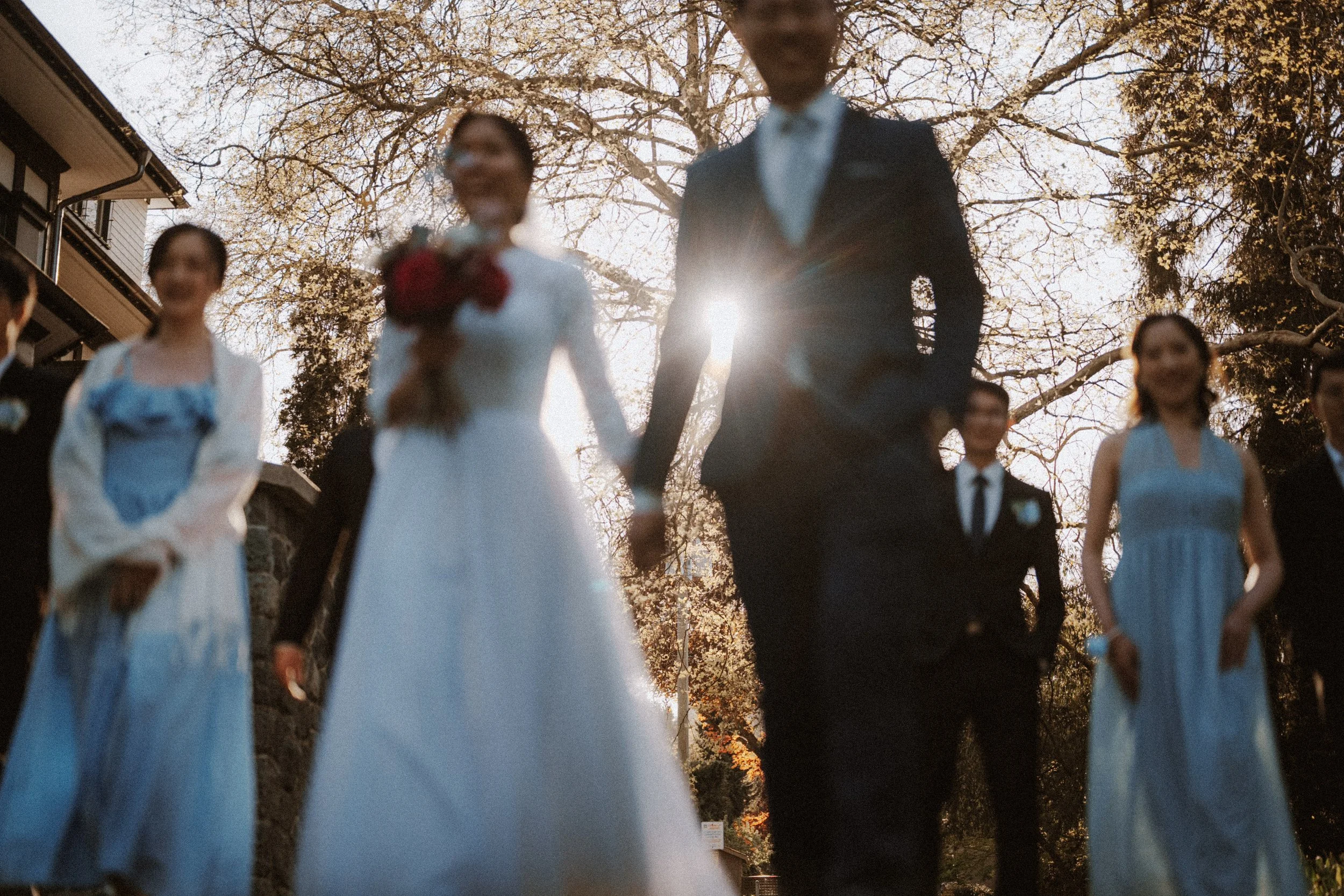  A unique, artistic shot capturing the motion and emotion of the couple and the wedding party walking in brilliant, warm light. 