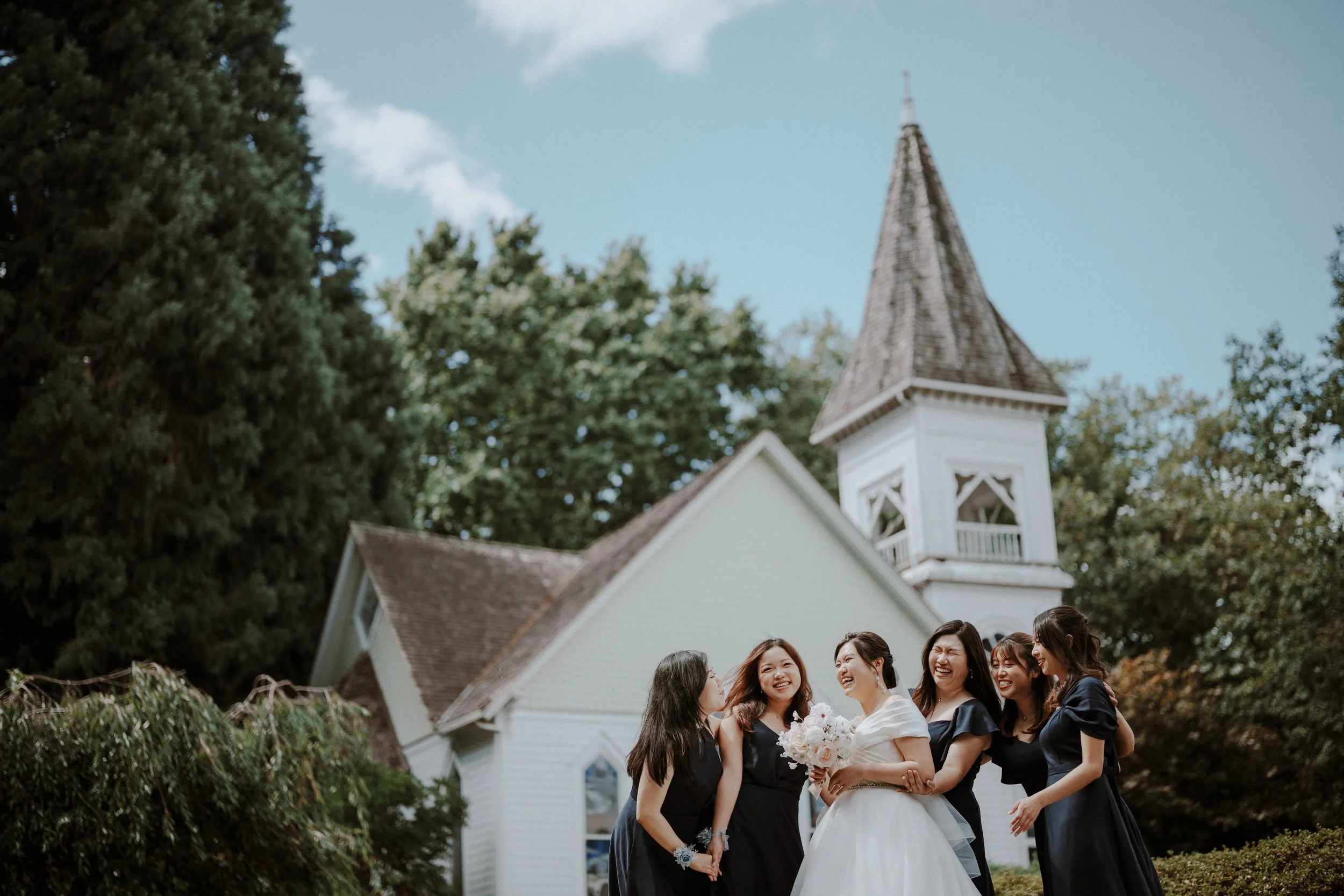  The bride shares a moment of pure joy and laughter with her bridesmaids. A beautiful group portrait taken outside the historic  Minoru Chapel . 