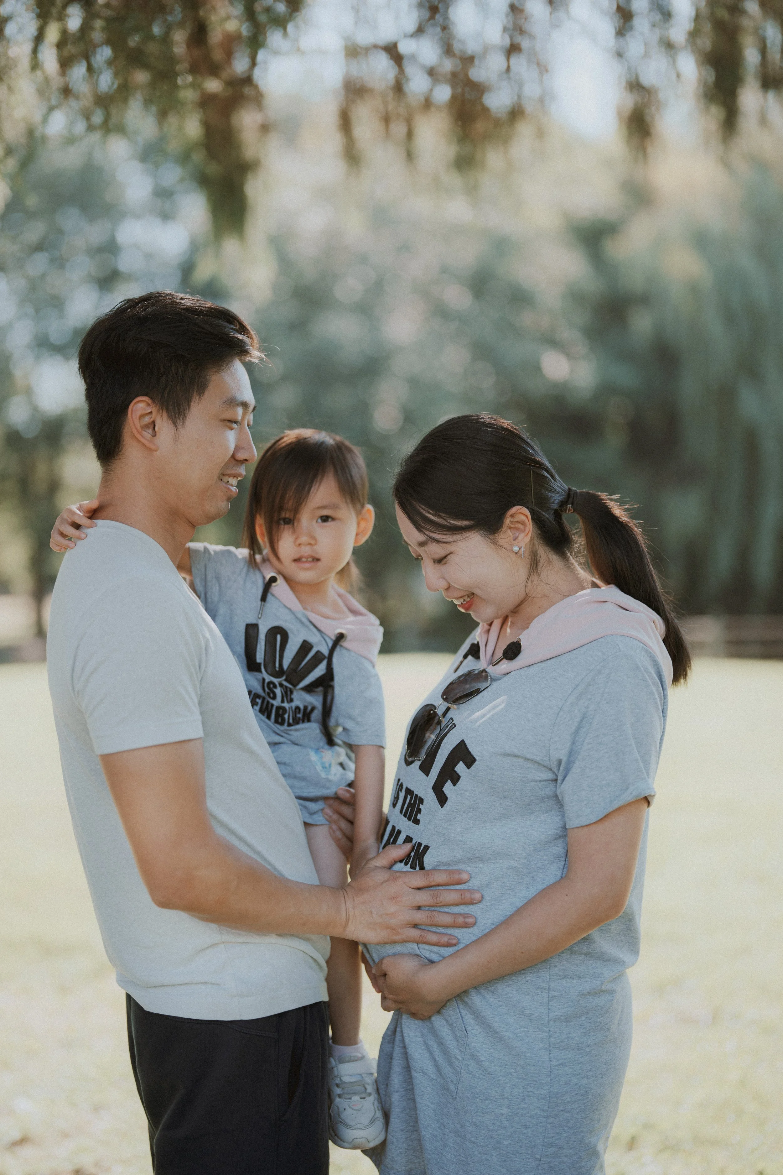  I love how gentle this moment is. The way the hands rest on the belly, the child held close, the matching shirts—it’s quiet, but full of feeling. 