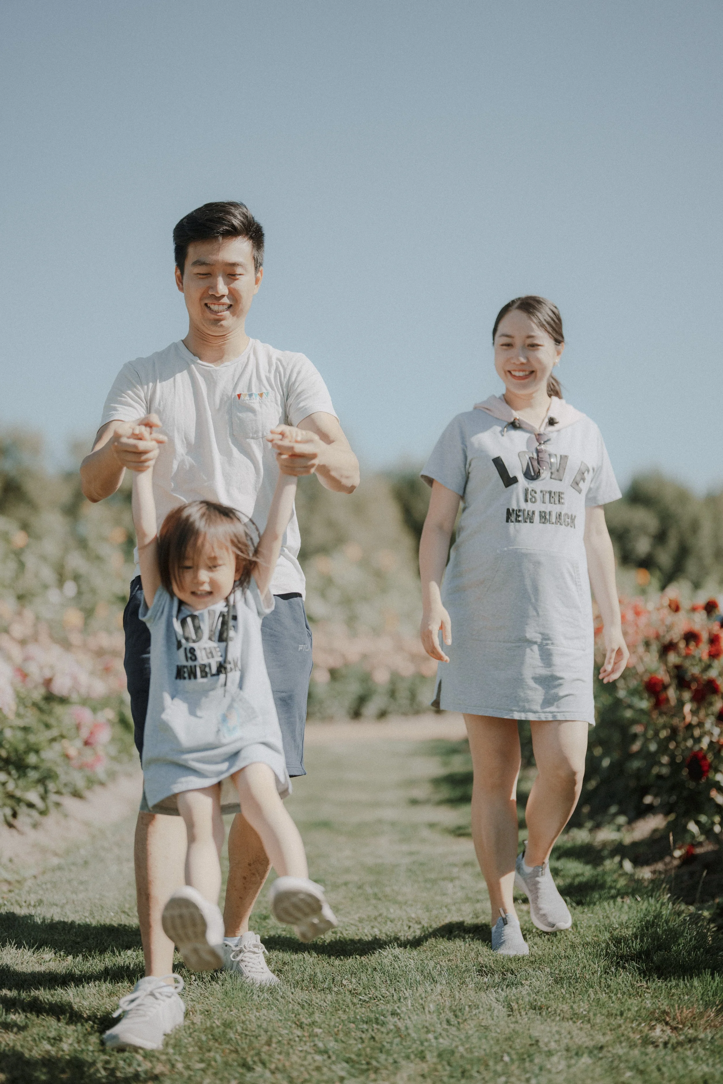 He lifted her off the ground and she laughed. The light, the flowers, the matching outfits—it was playful, warm, and full of joy. I just followed them with my lens. 