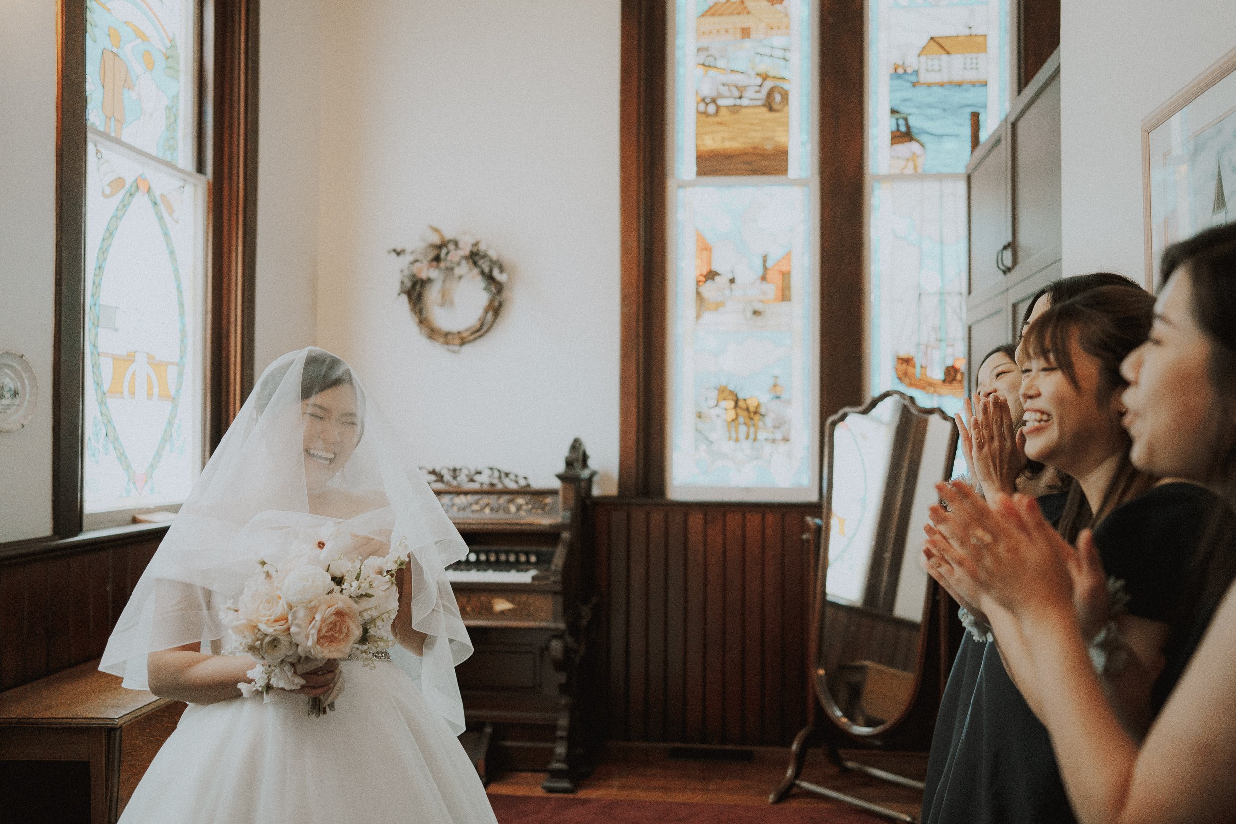  The  bride  and her bridesmaids sharing a joyful, candid moment in the church room. 