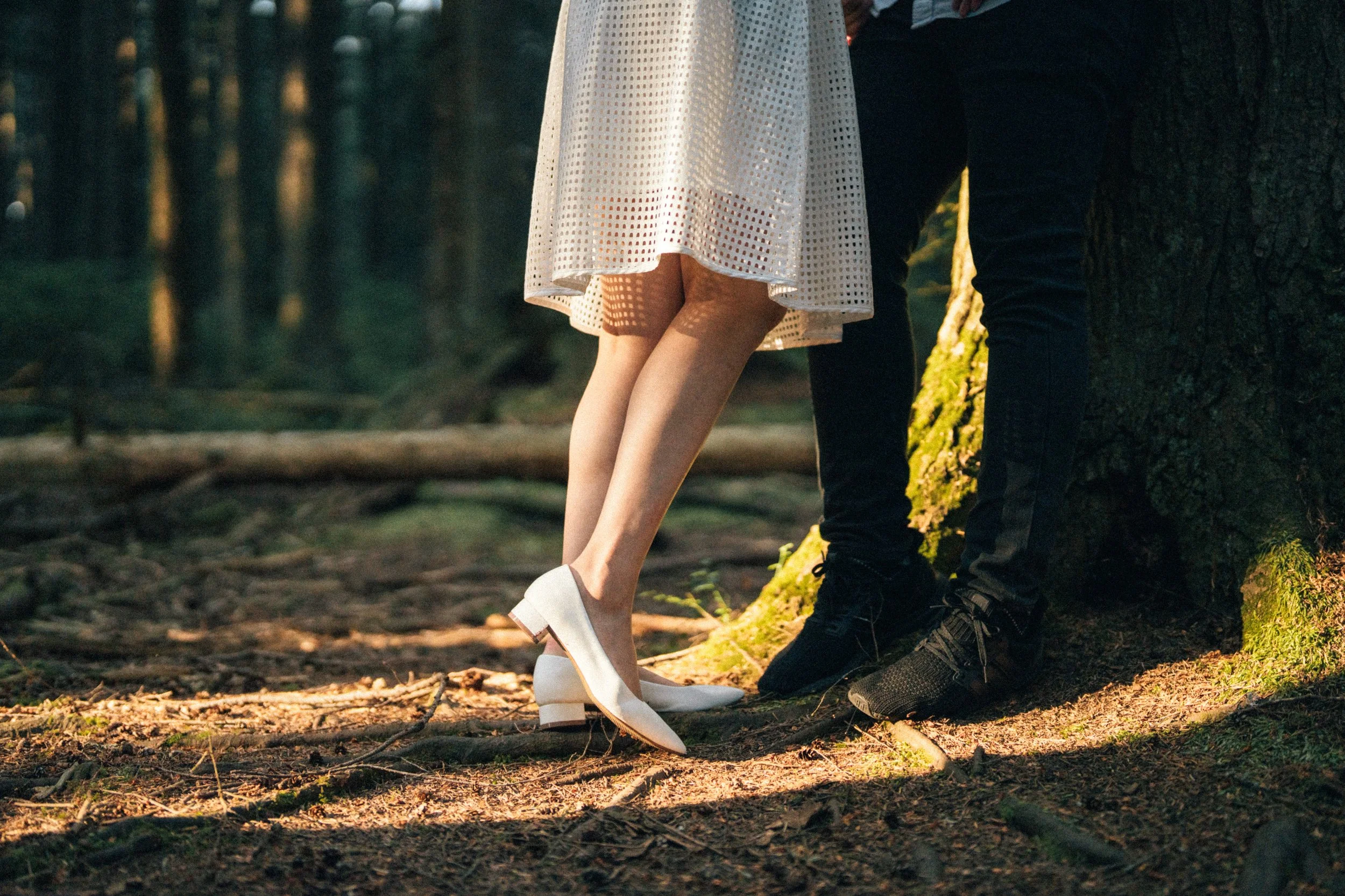  An intimate detail shot of the couple's legs, capturing a quiet moment in the warm forest light. 