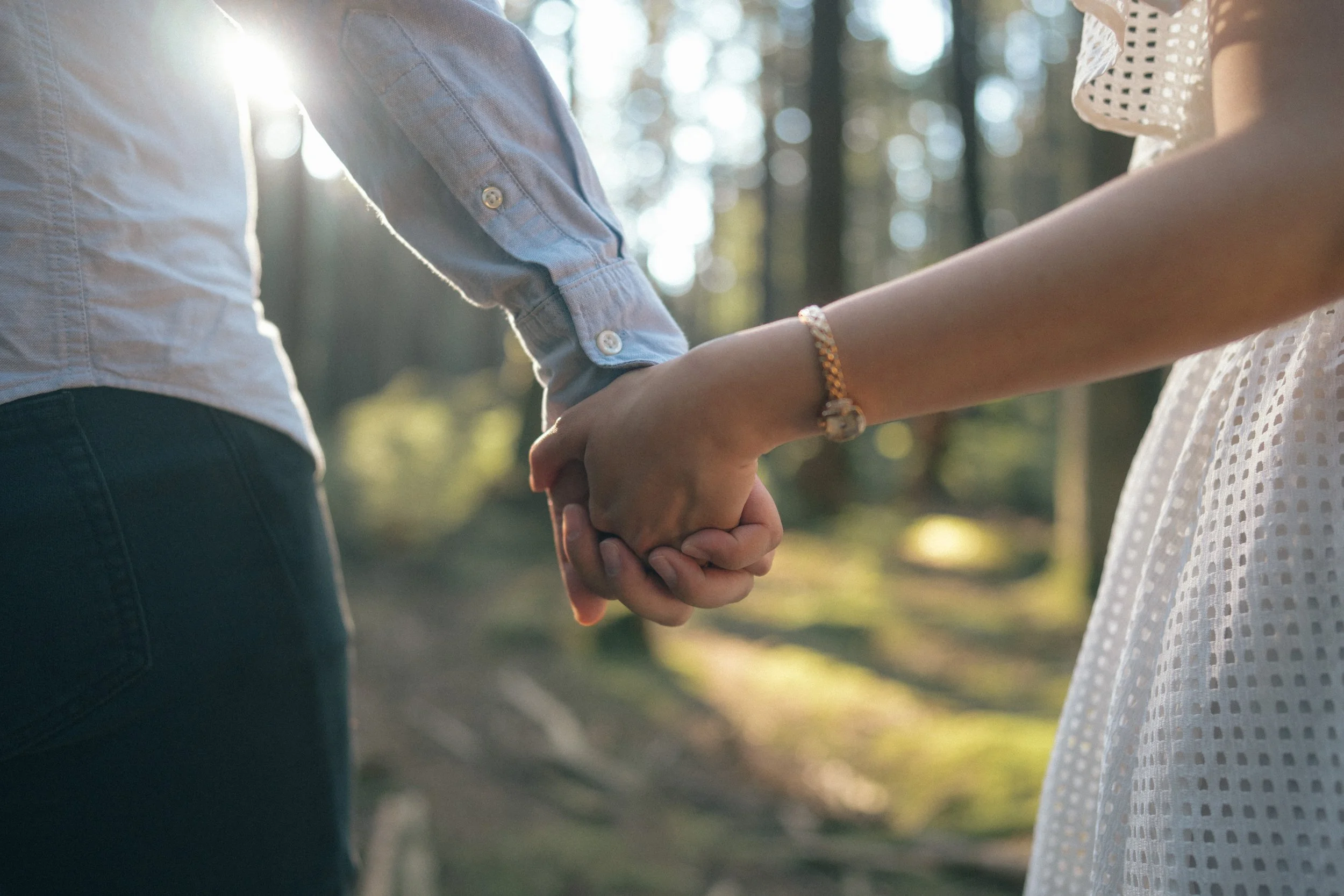  A romantic detail shot focusing on the hands and the brilliant golden light filtering through the trees. 