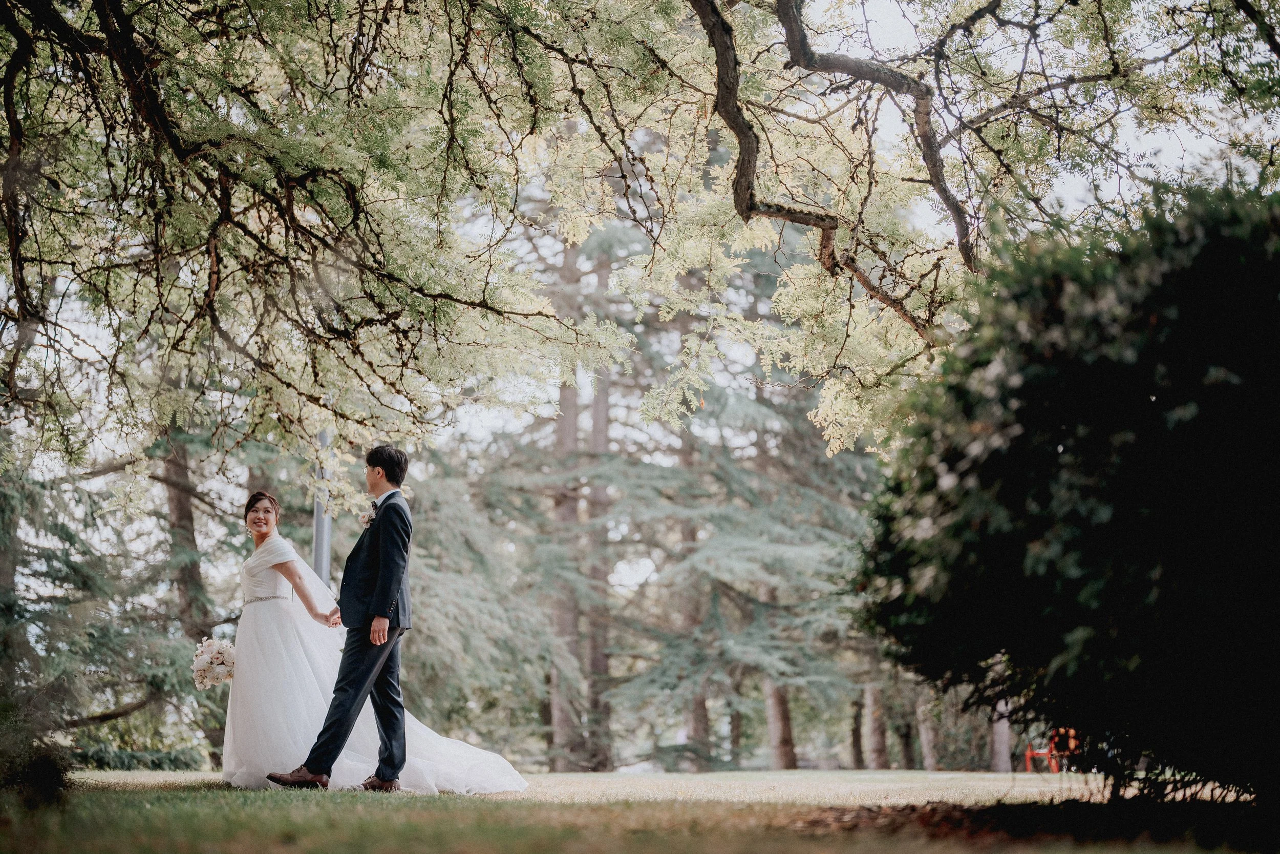  A romantic portrait under the canopy of trees, the couple holding hands on the church grounds. 