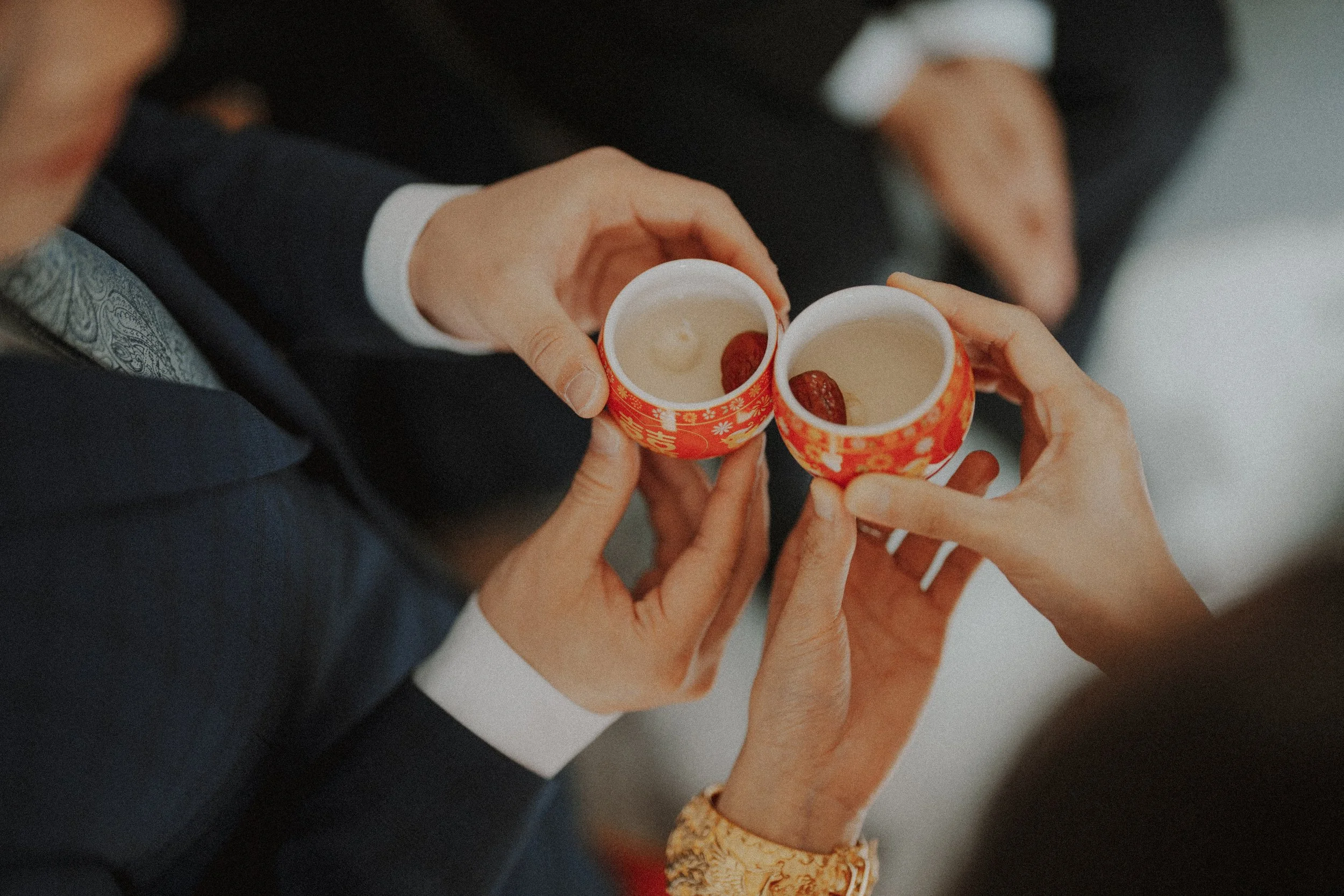  A beautiful detail shot of the couple's hands and the  traditional Chinese tea cups . 