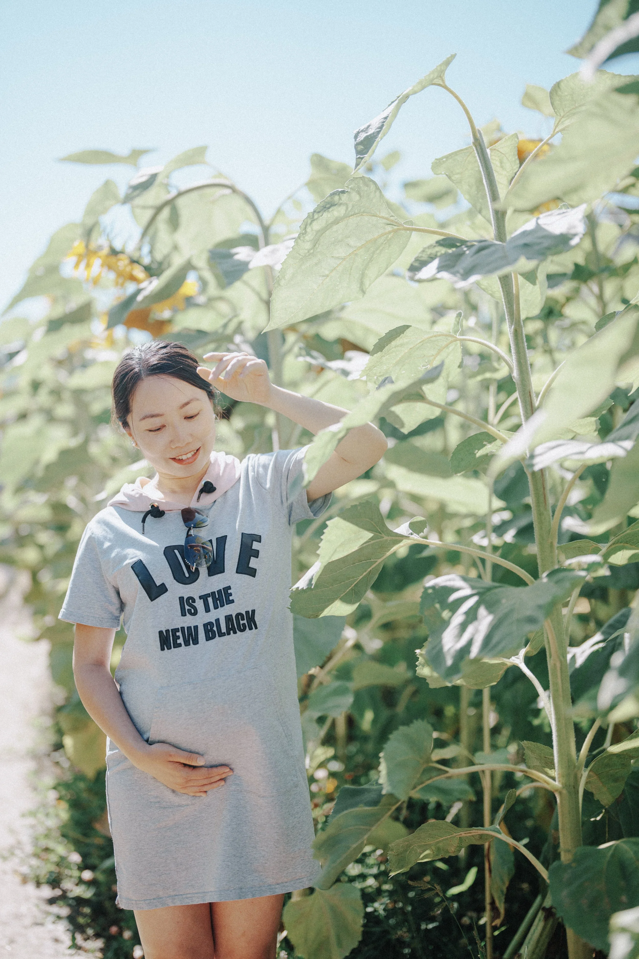 Person standing in sunflower field with hand on belly at Richmond Country Farms