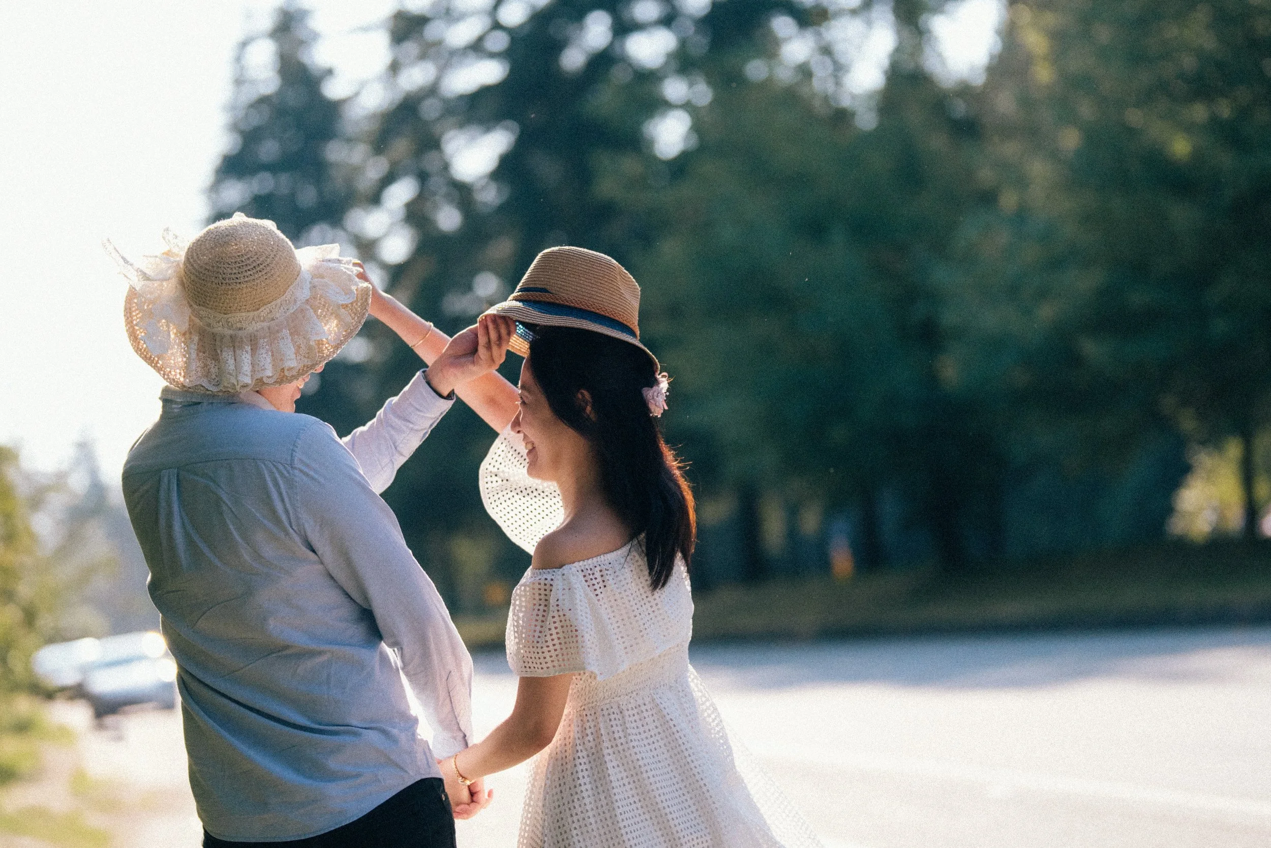  A playful, candid moment as the couple adjusts each other's straw hats in the sunlight. 