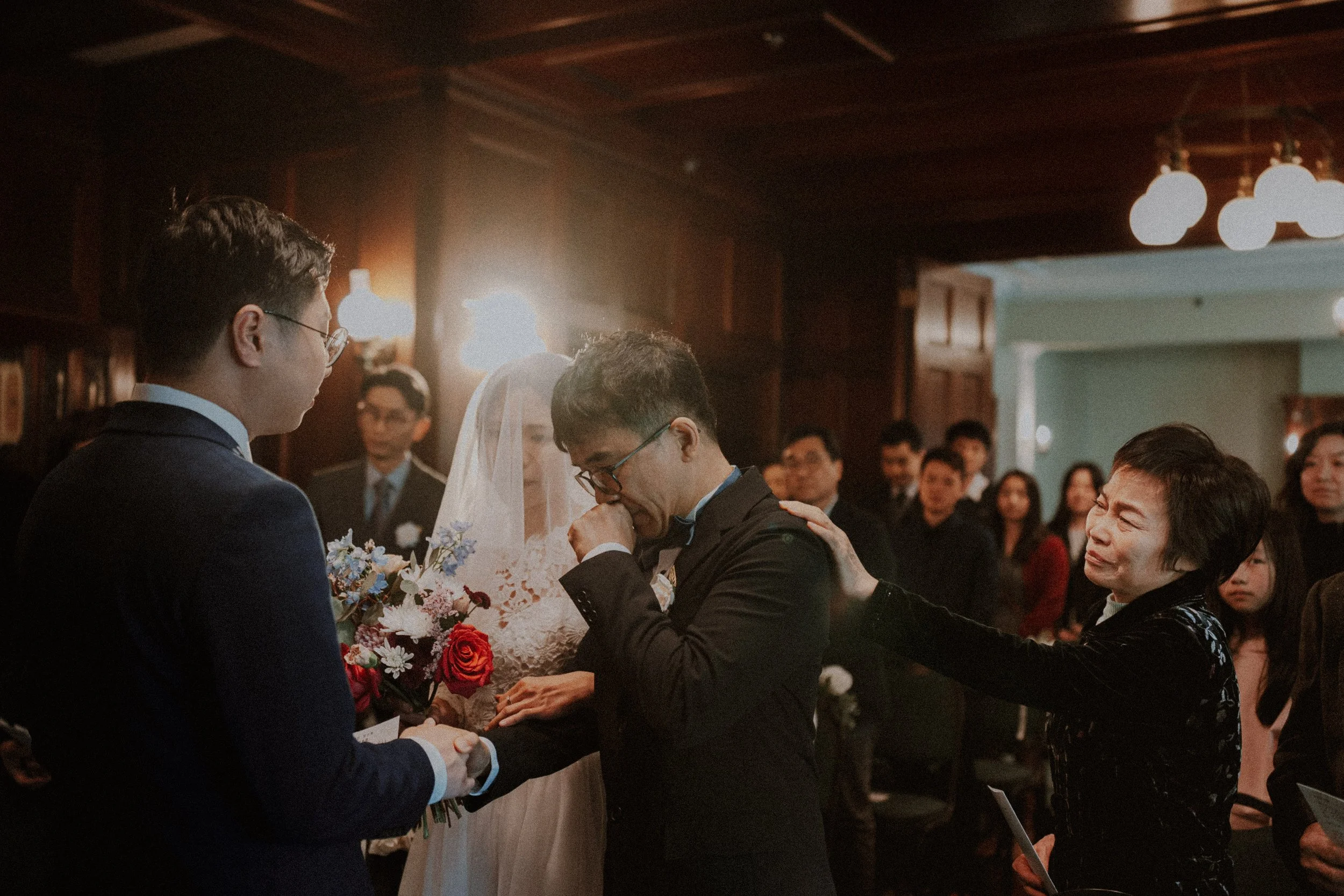  A deeply moving moment: The groom's mother gently comforts the bride's father as he hands his daughter away. Capturing the shared emotion and strong family bond during the ceremony. 