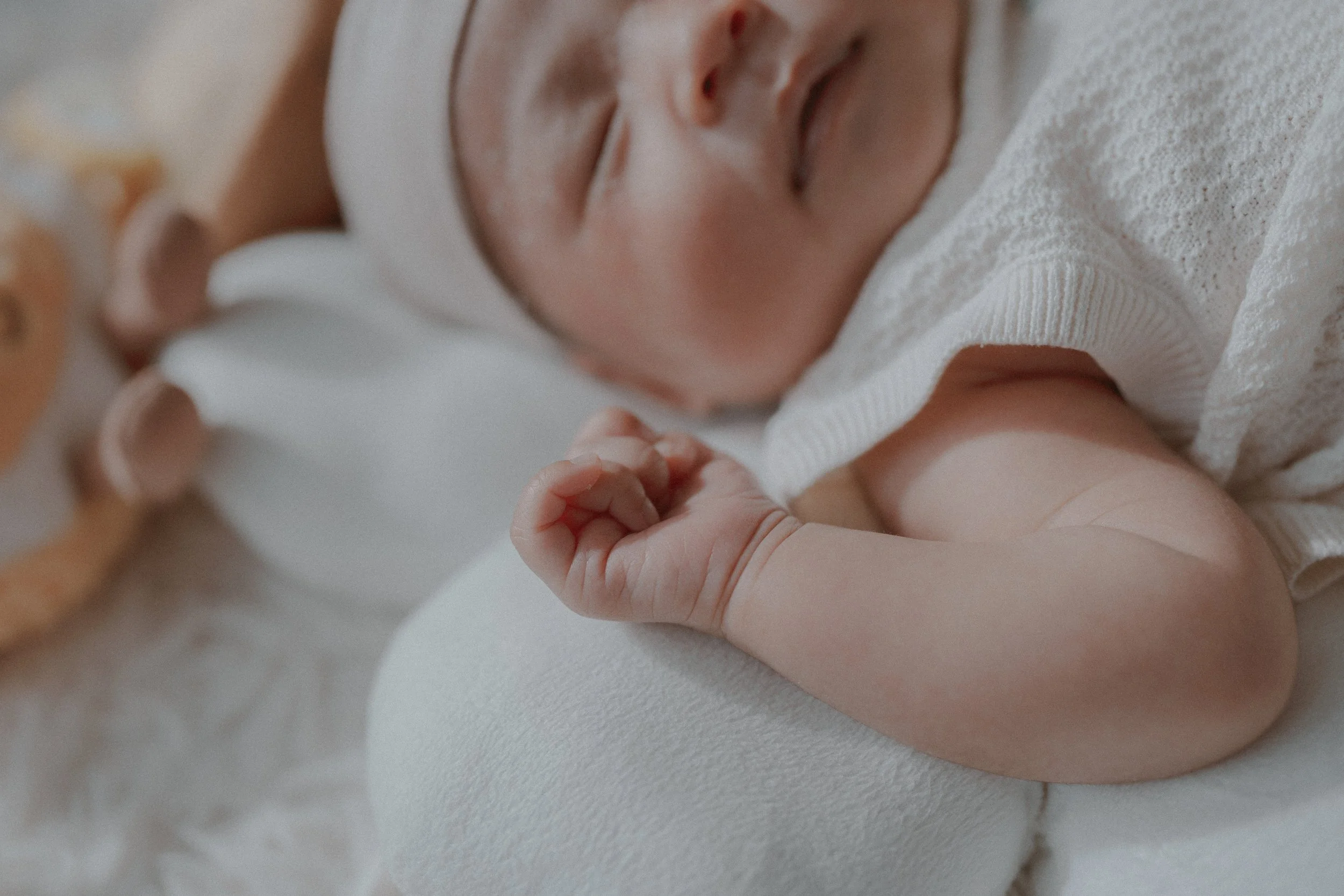 Close-up of baby hand with soft textures and warm hues, captured in natural light for Tata & Lemon's session.
