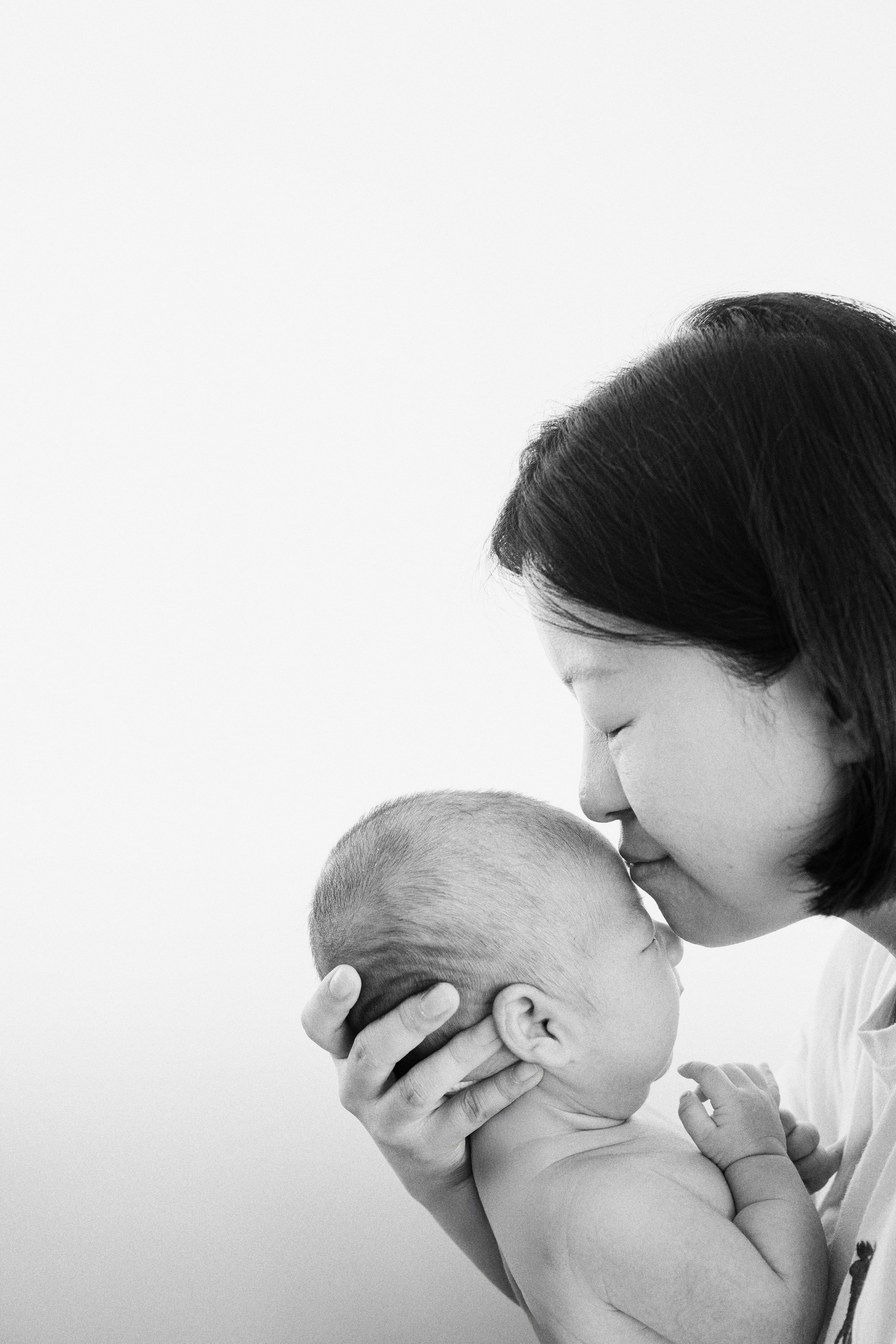  The pure love of a mother: A gentle kiss on baby Apollo's forehead, captured in timeless black and white. 