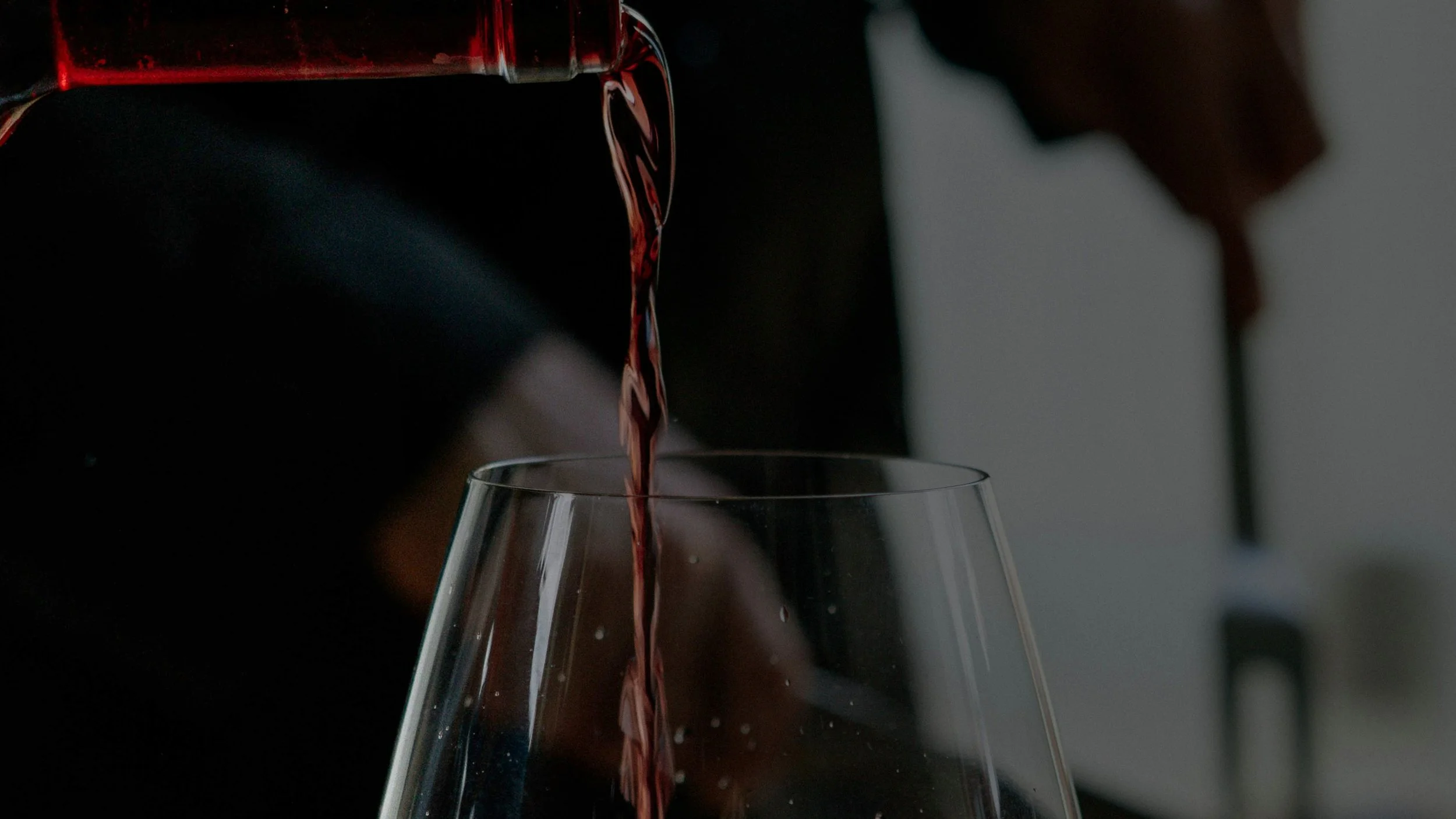 Red wine being poured from a bottle into a wine glass.