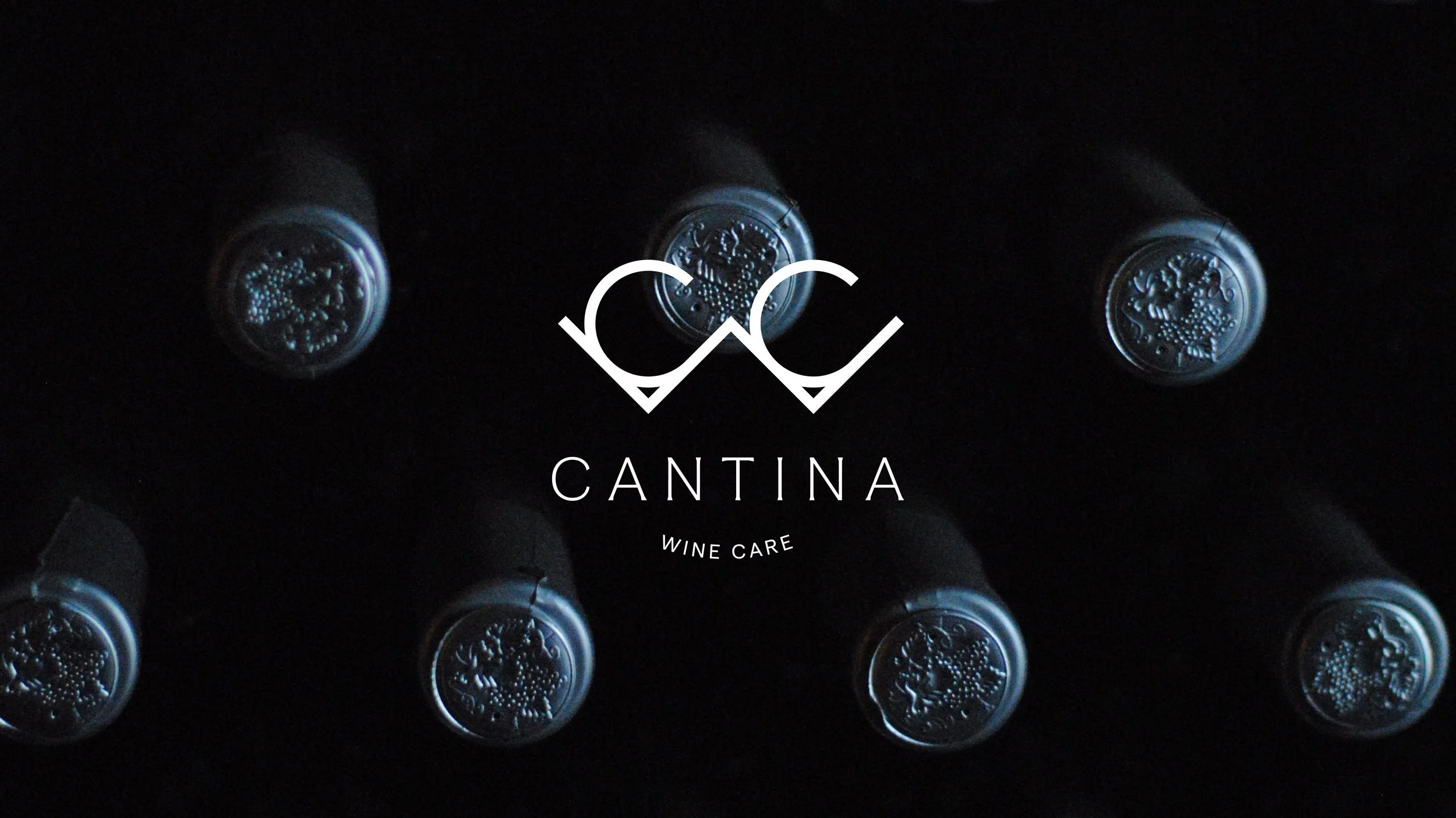 Six wine bottles with the logo of Cantina Wine Care in the center, viewed from the top against a black background.